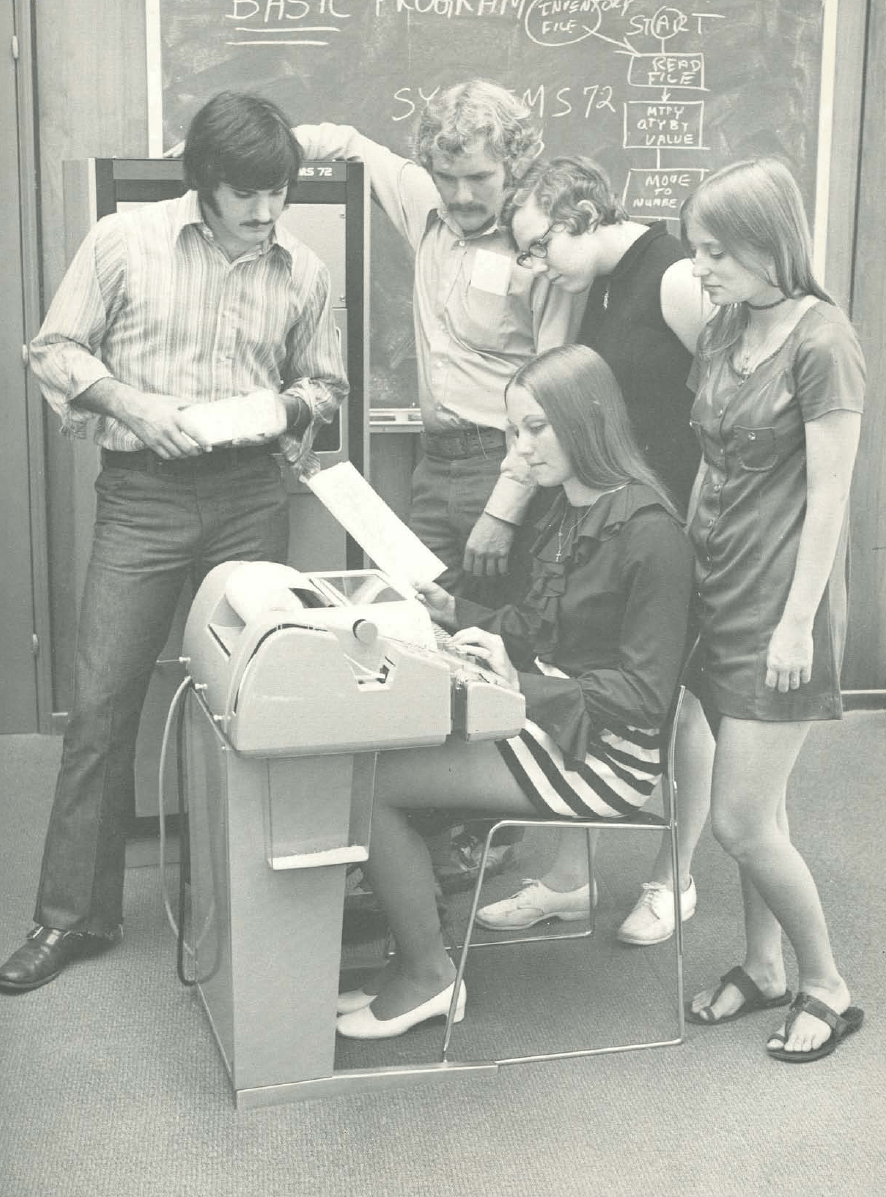 weird vintage photo of women in tiny miniskirts at huge old computers