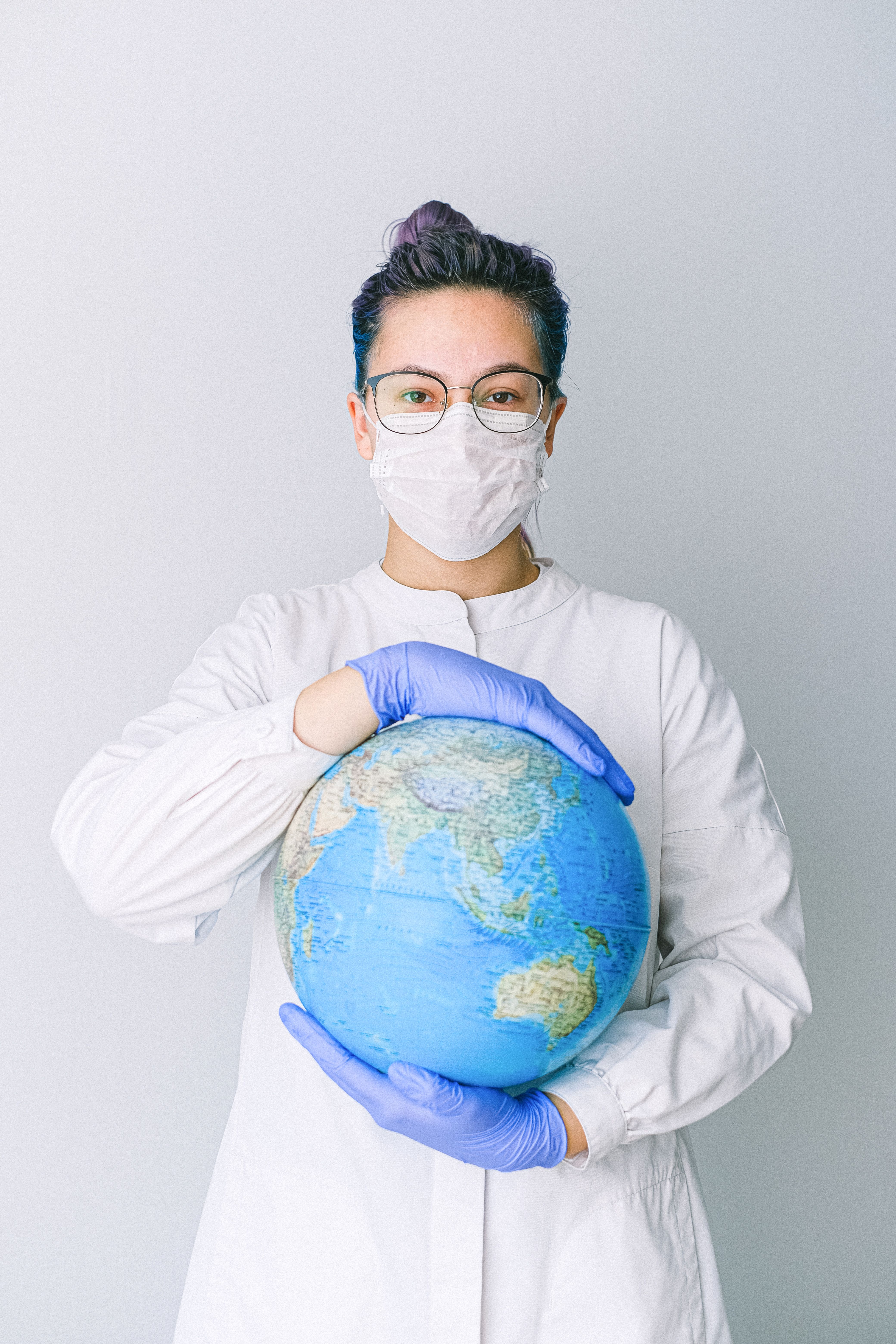 Person With a Face Mask and Latex Gloves Holding a Globe · Free