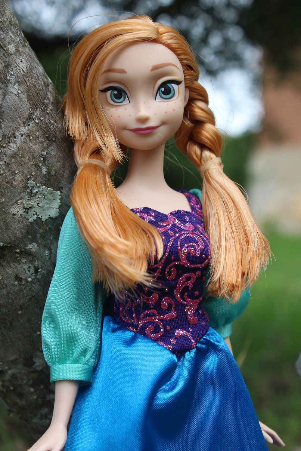 female doll in green dress laying on grass field photo