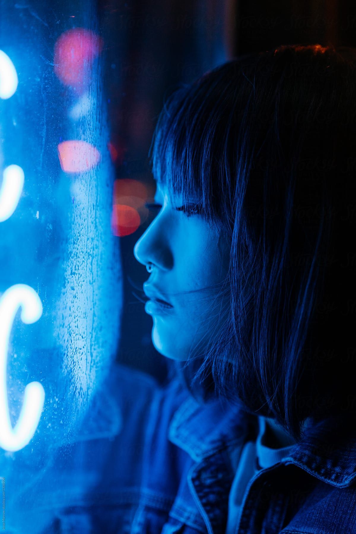 Portrait of young female asian woman next to blue neon lights in urban city environment