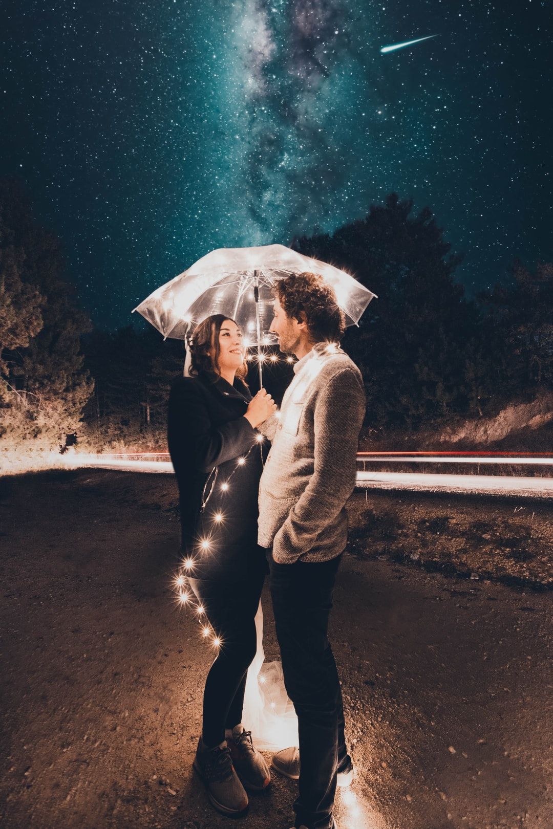 couple under clear umbrella with string lights during night photo