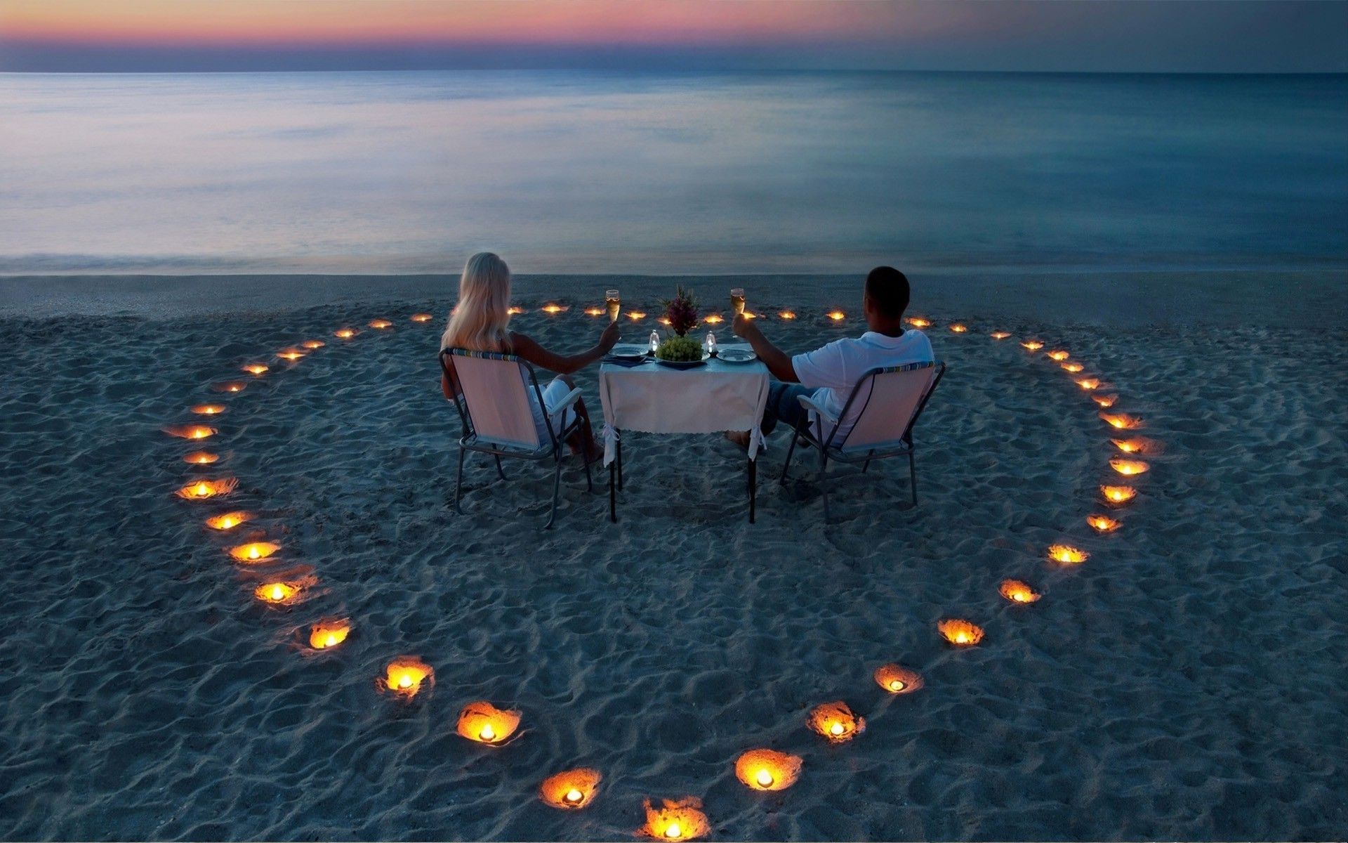 Two lovers for a romantic dinner among candles on the sea