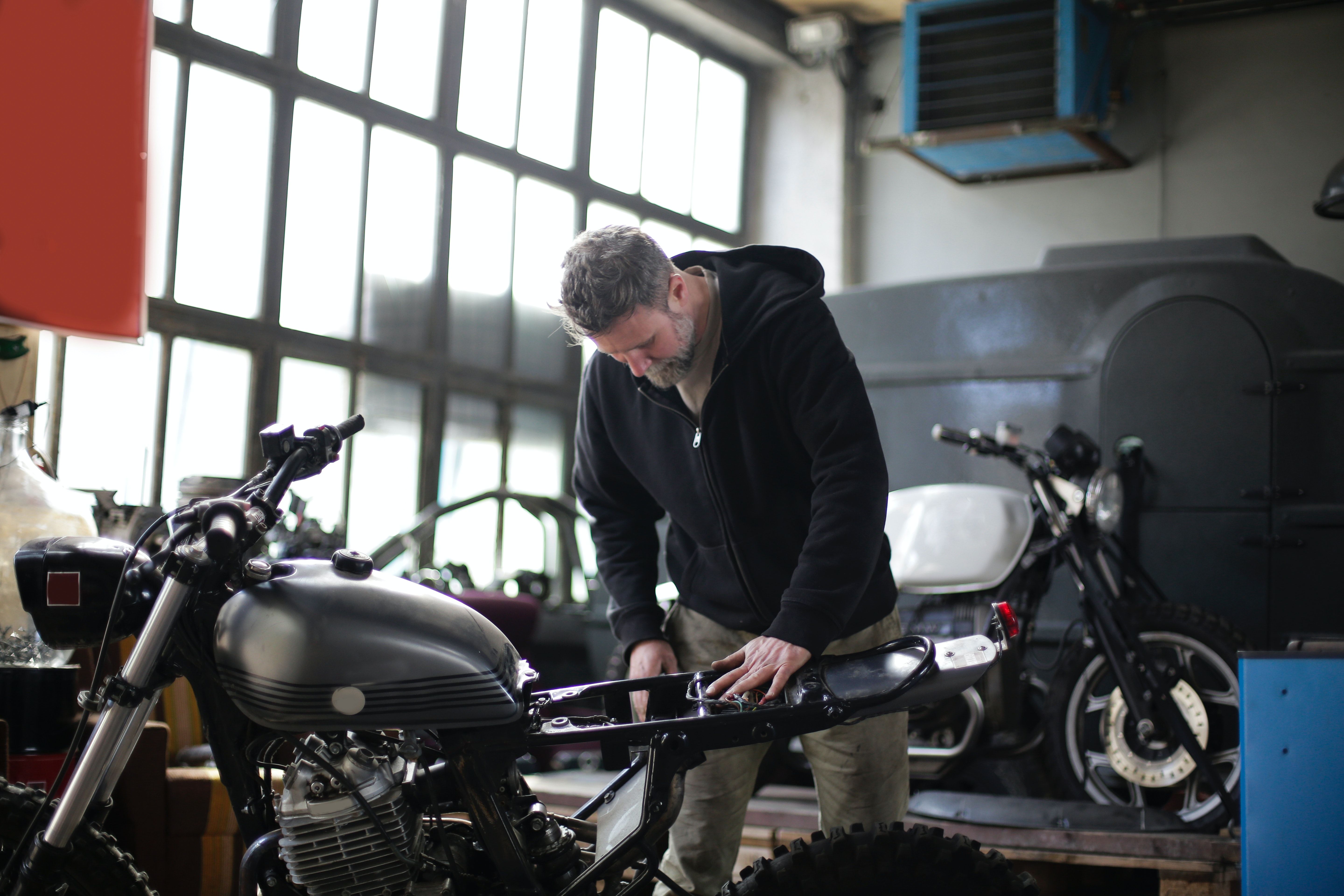 Serious adult male mechanic repairing motorbike in garage · Free