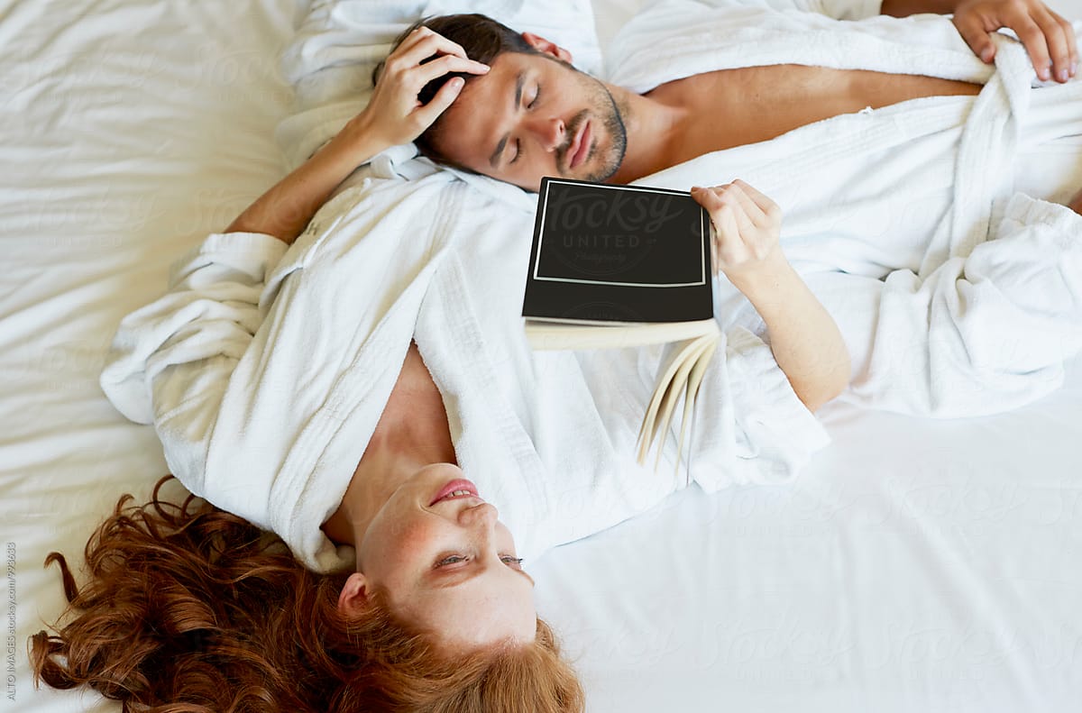 Woman Reading Book While Man Sleeping In Bedroom by ALTO IMAGES, Book
