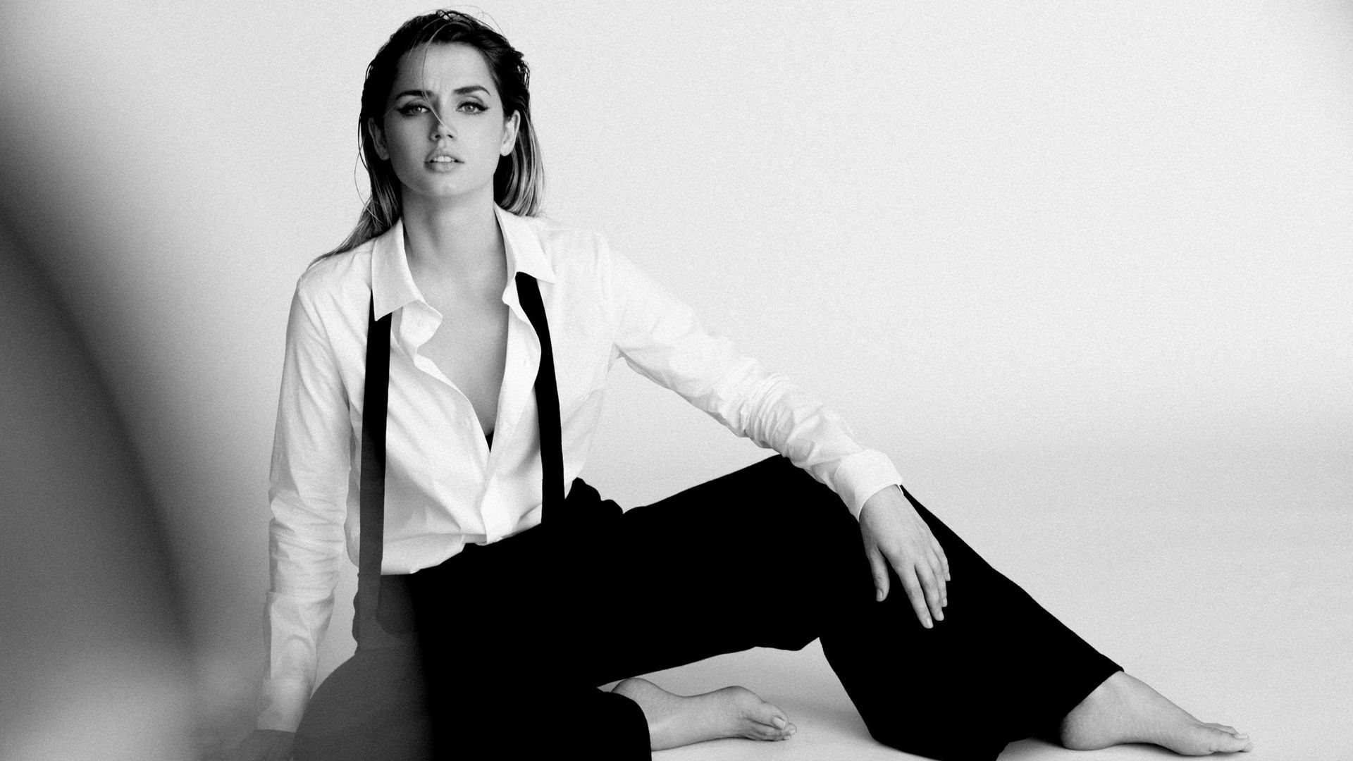 Ana De Armas Is Sitting On The Floor And Wearing White Shirt And Black Pant With Shoulder Belt HD Celebrities Wallpaper