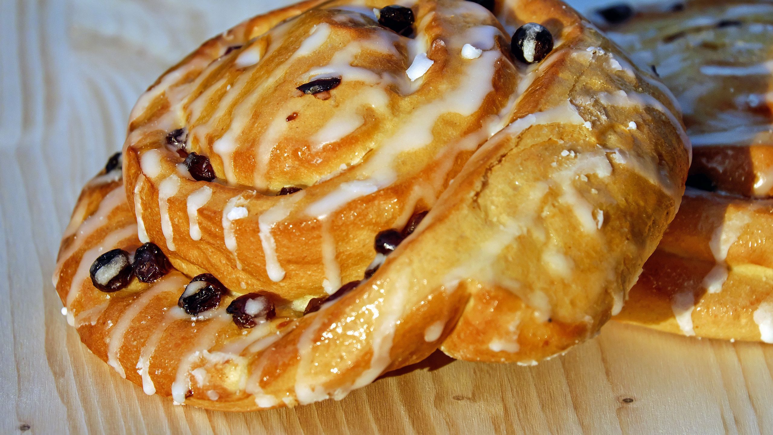 Download wallpaper 2560x1440 bun, raisins, glaze, pastry widescreen 16:9 HD background