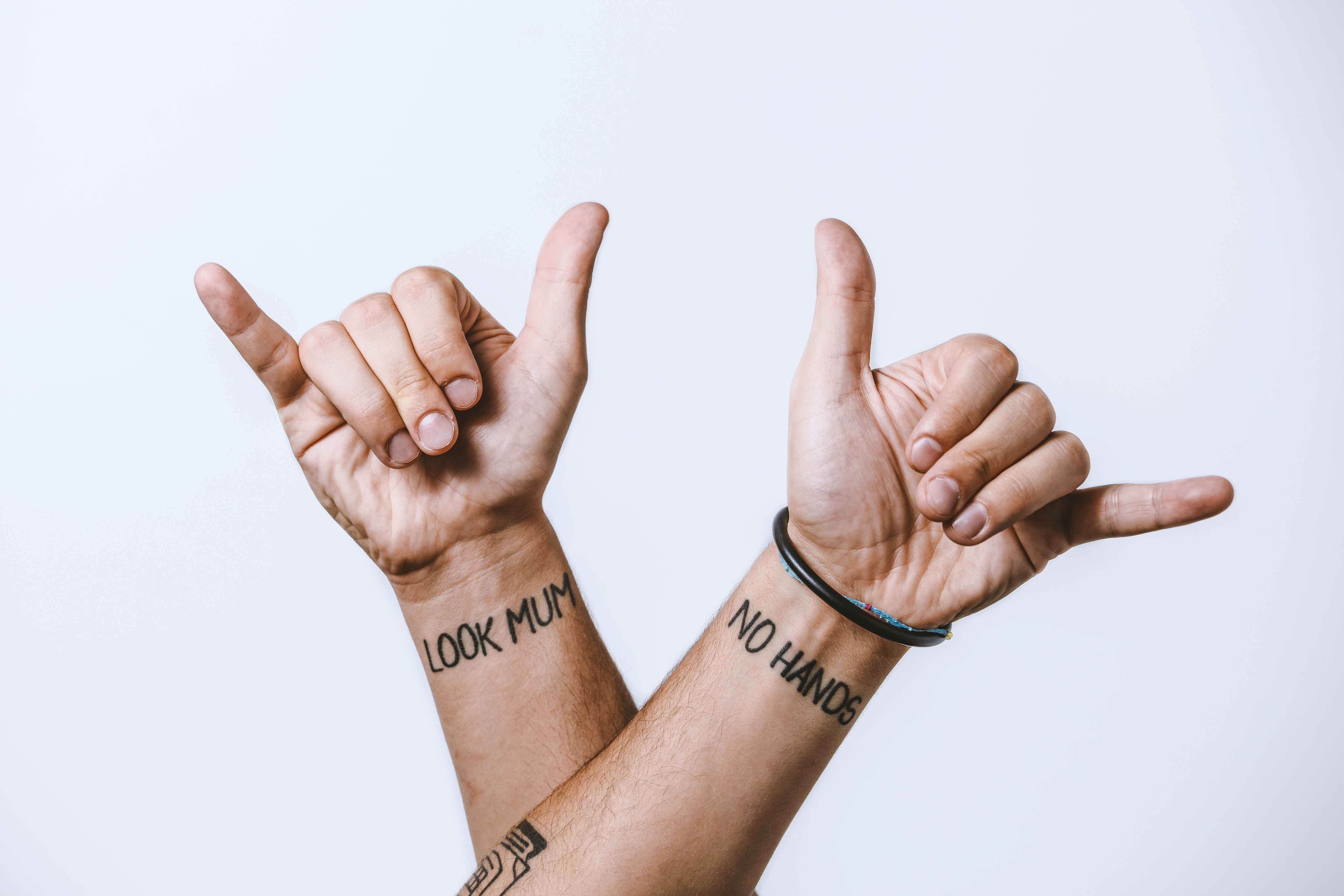 Crop tattooed man hands showing hang loose gesture with fingers · Free