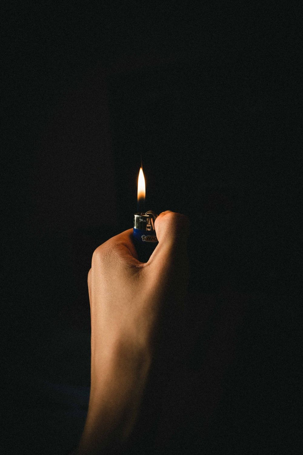 person lighting lighter on black background photo