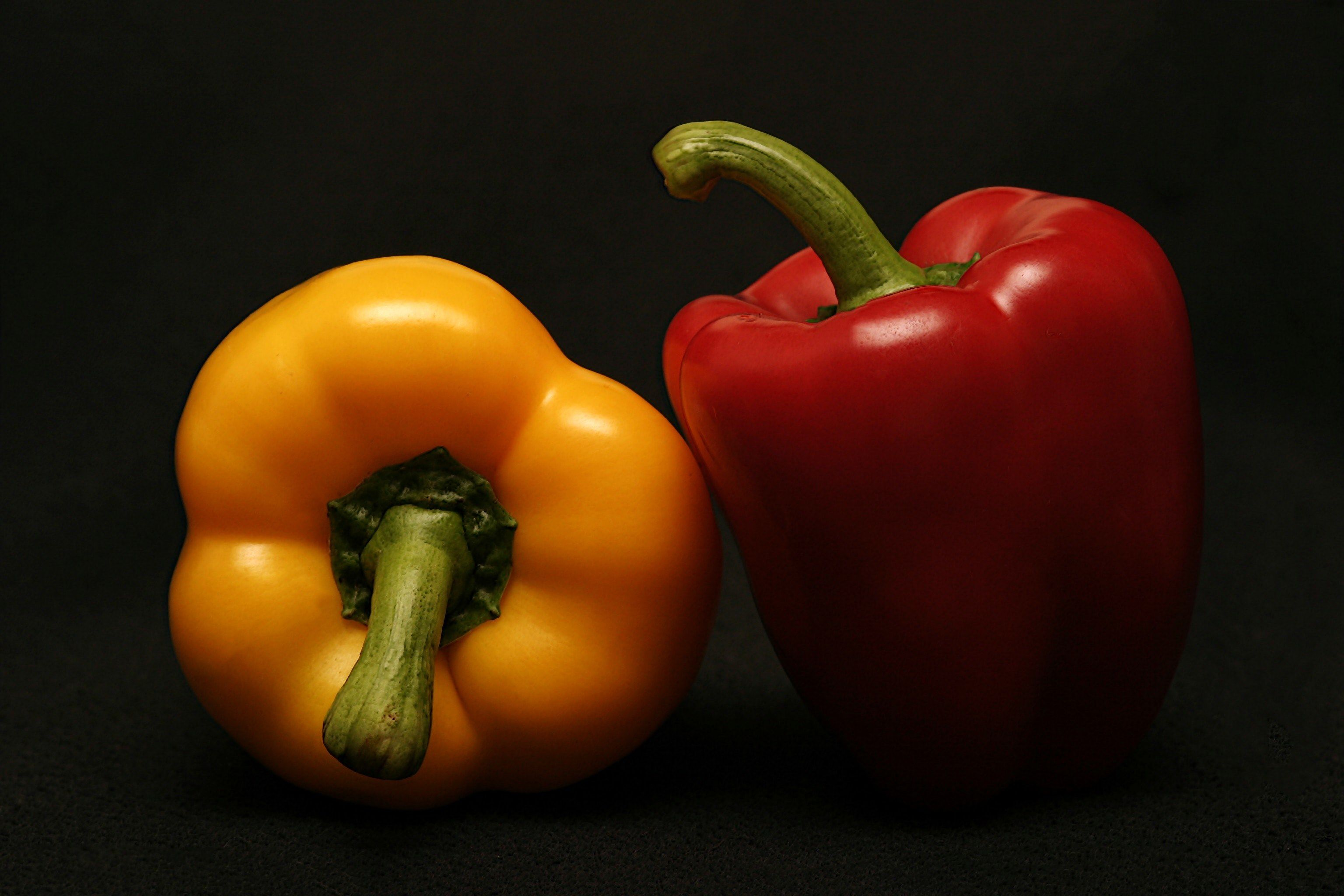 Wallpaper / red and yellow bell peppers in the shadows against a black background, fresh sweet peppers 4k wallpaper