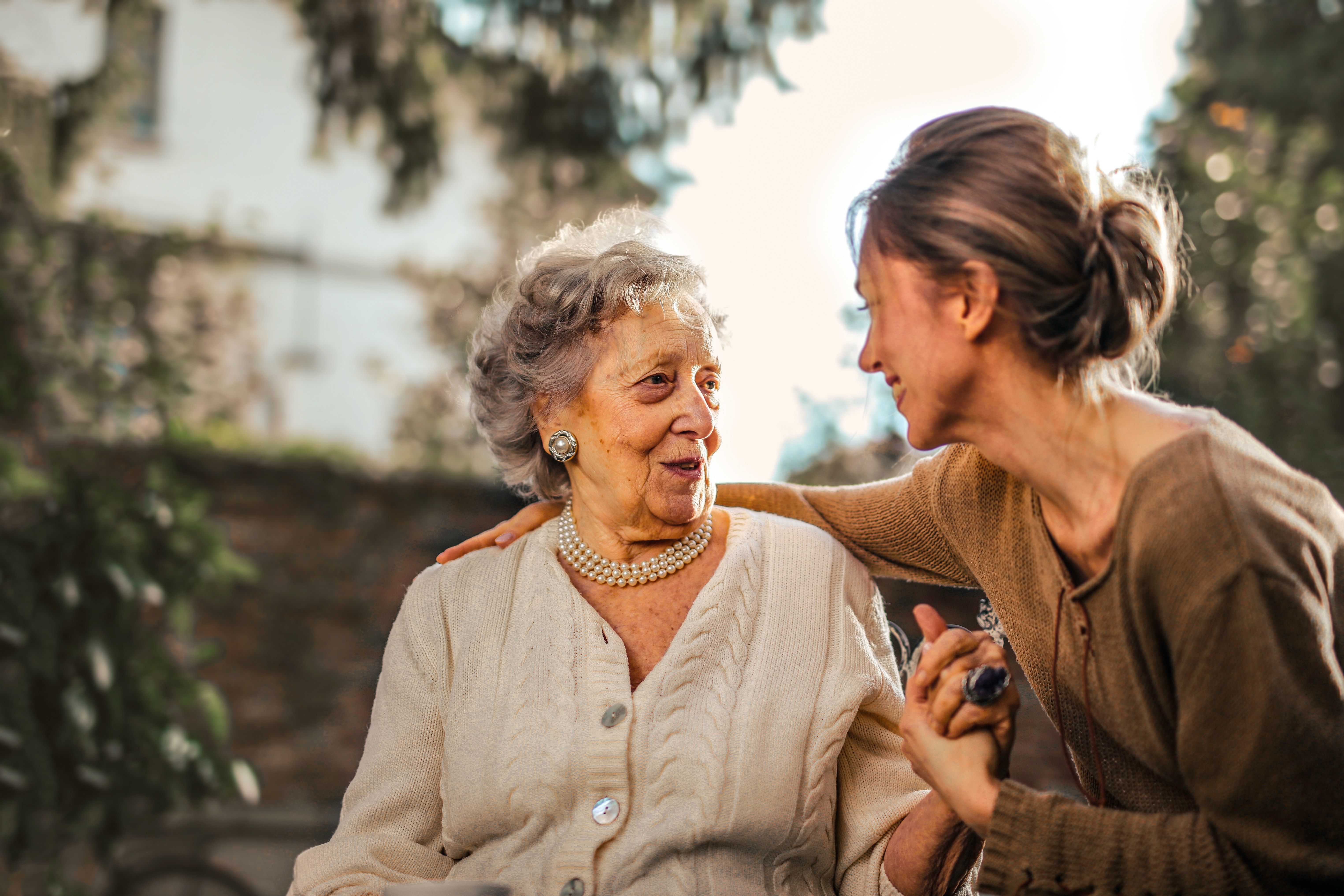 Joyful adult daughter greeting happy surprised senior mother in garden · Free