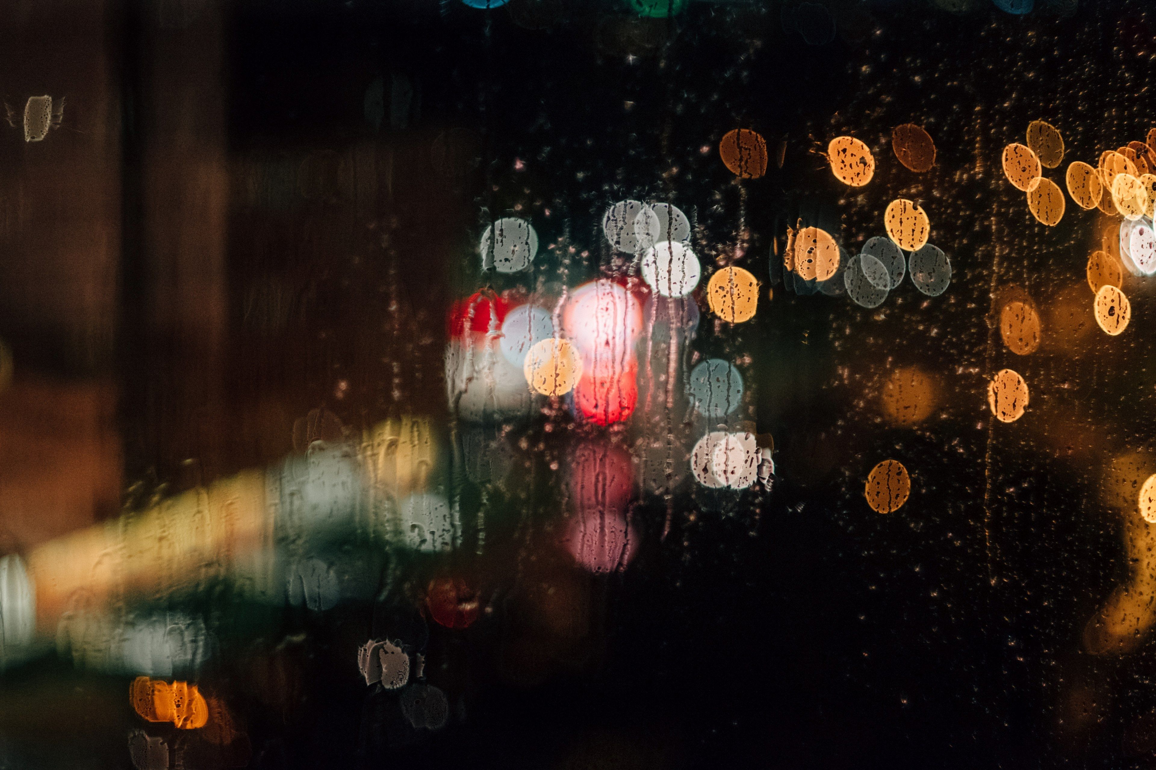 Wallpaper / a rain streaked window with a bokeh effect, lights behind a rainy window 4k wallpaper