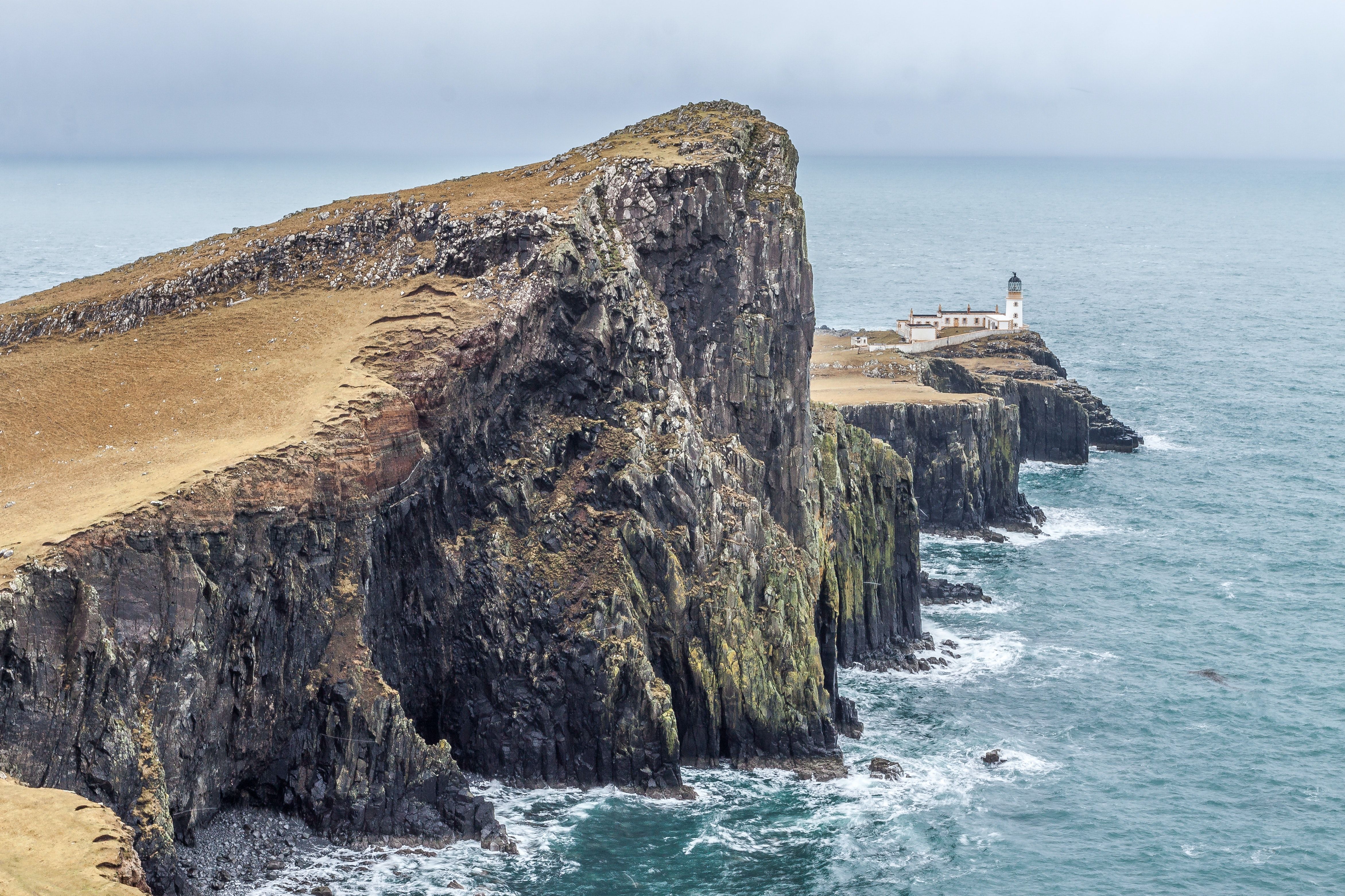 Lighthouse on Near Body of Water Between Rock Formation · Free