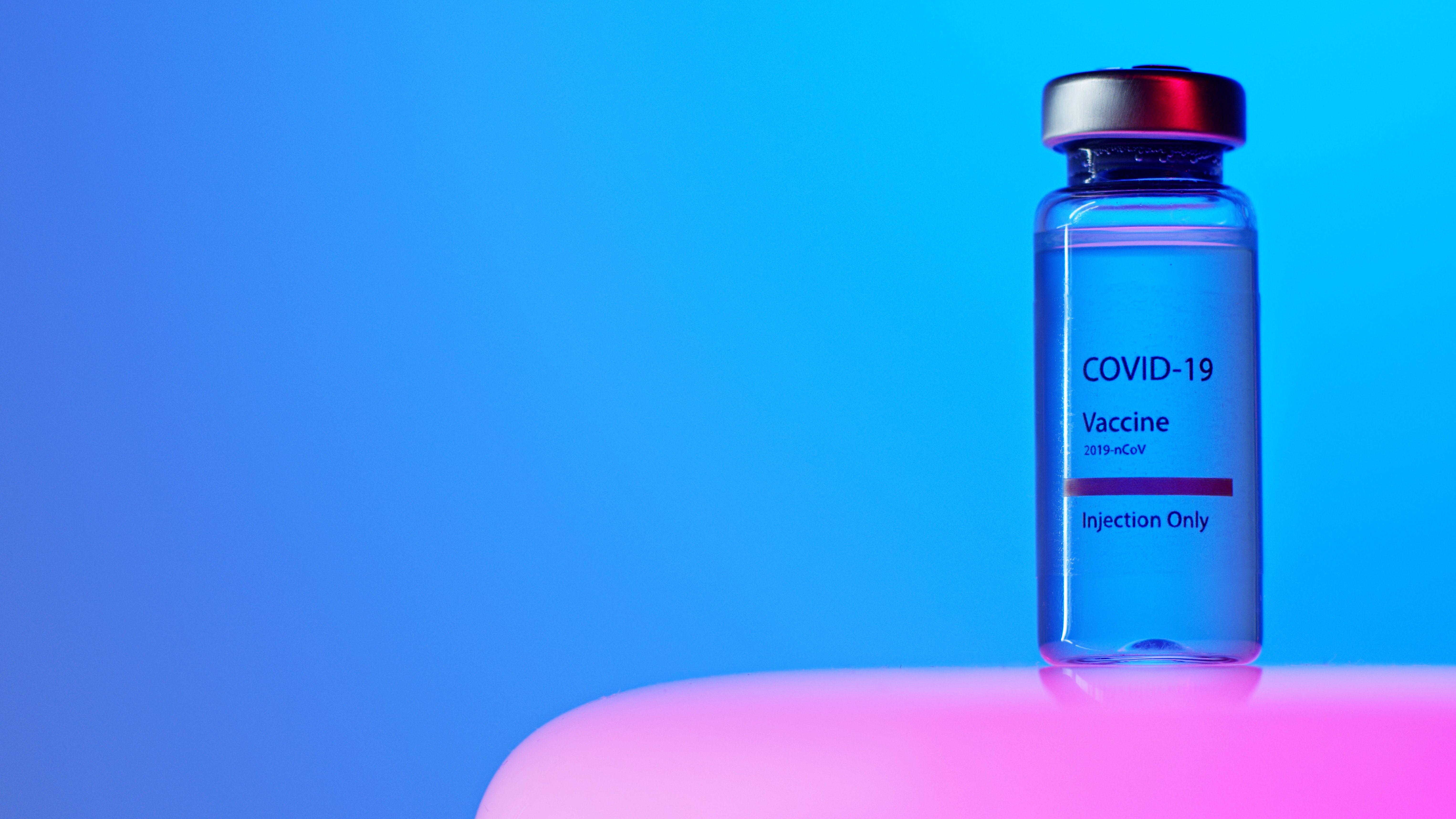 A Close Up View Of A Covid 19 Vaccine Vial On Blue Background · Free