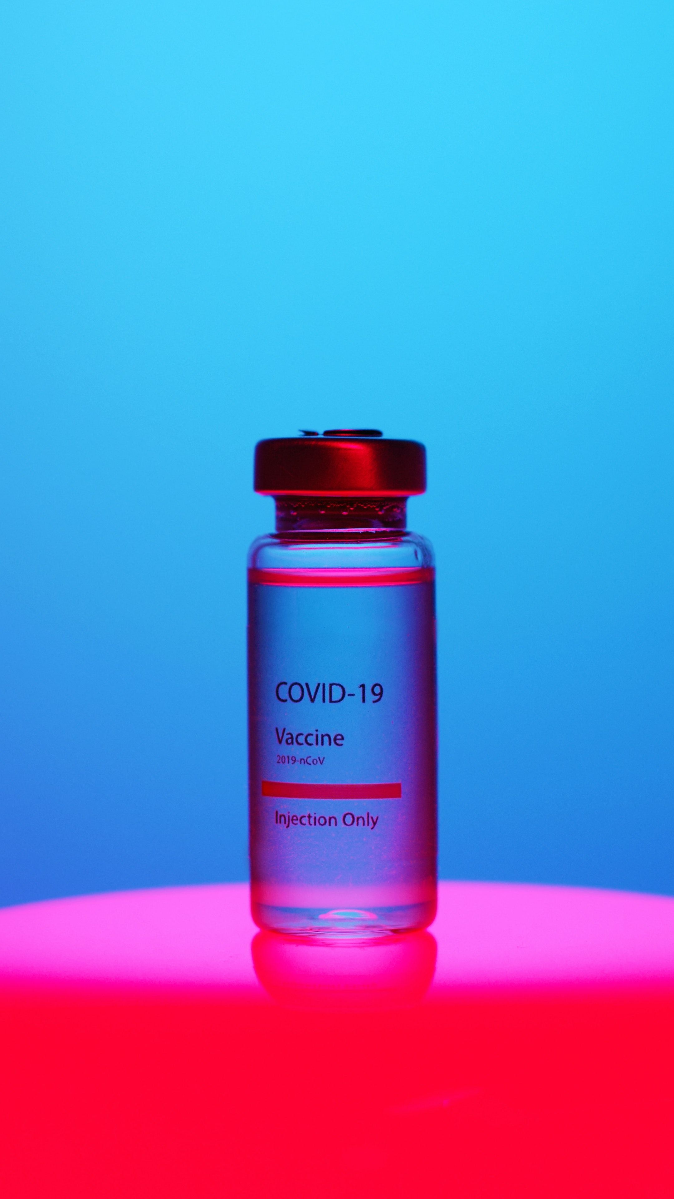 A Close Up View Of A Covid 19 Vaccine Vial On Blue Background · Free