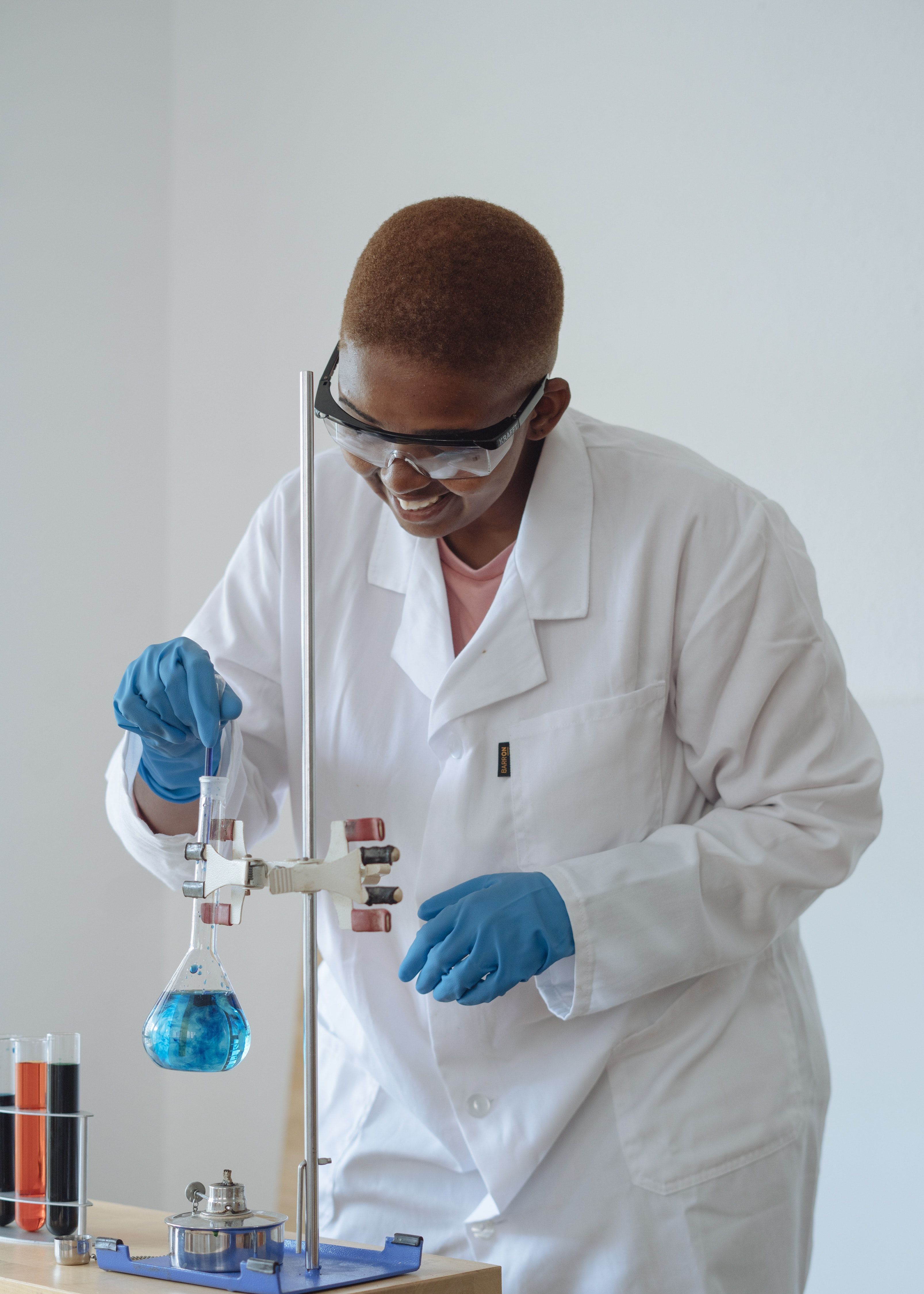 Smiling scientist examining chemical liquid in modern lab · Free
