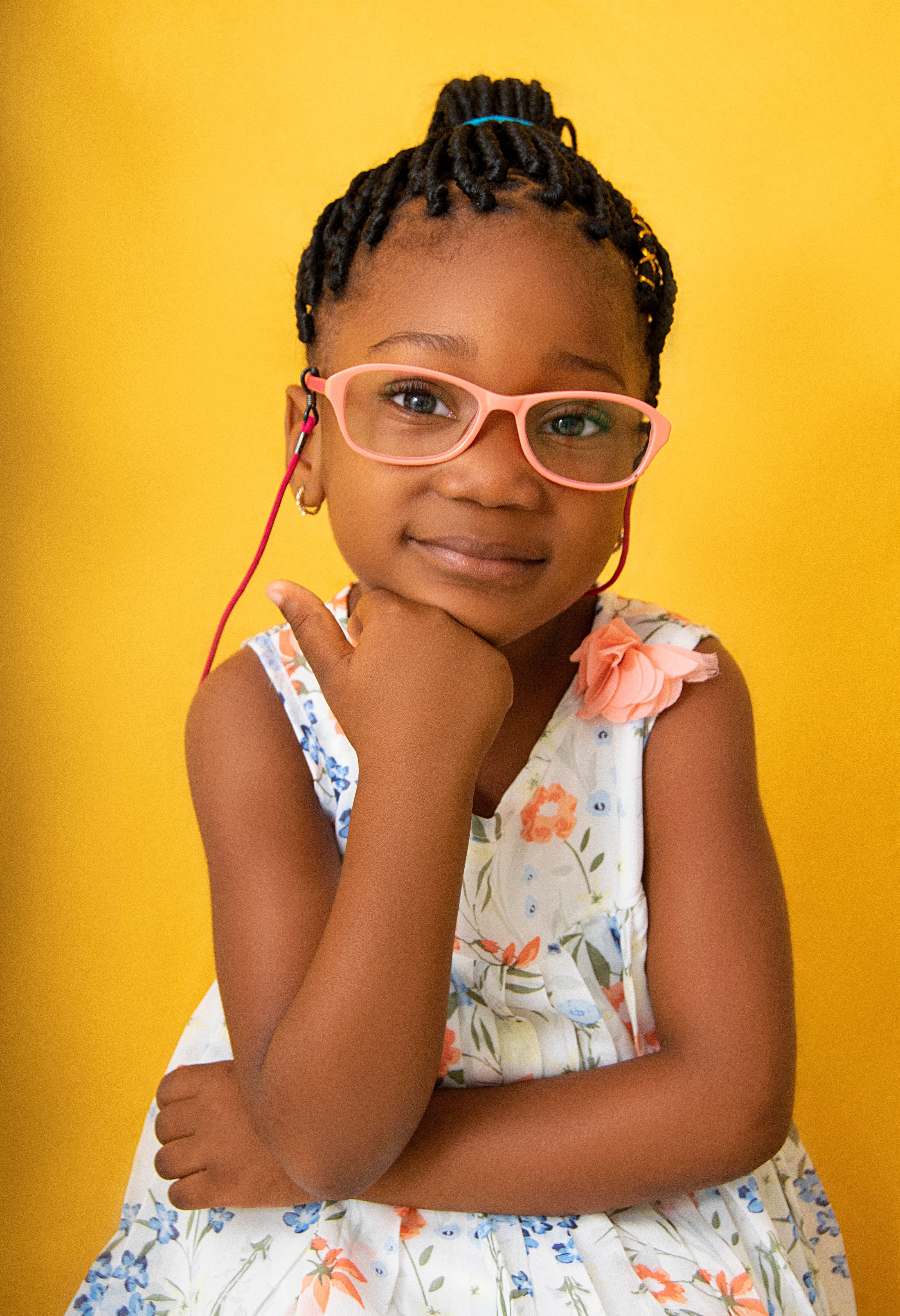 Smiling black girl in glasses touching chin and looking at camera · Free