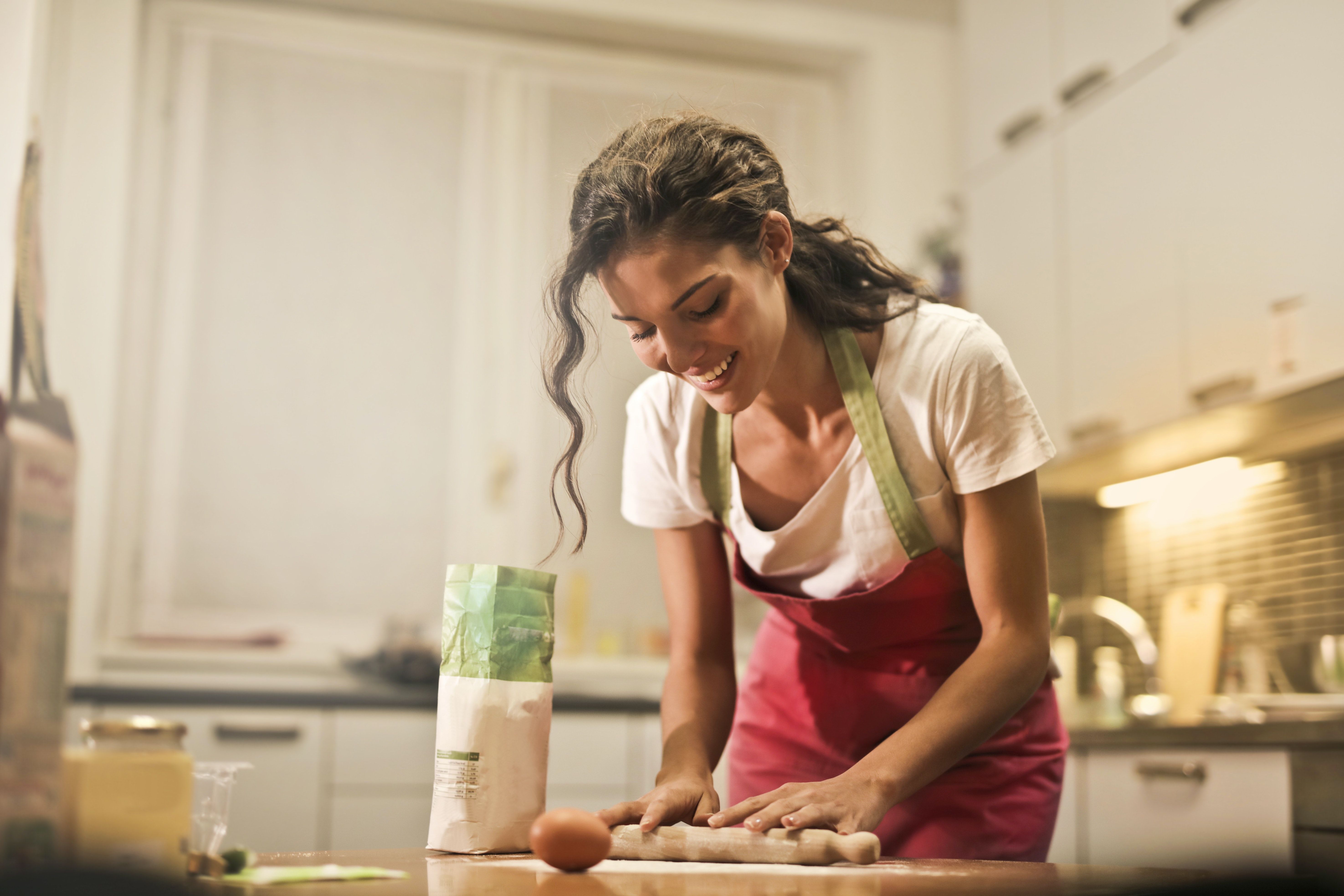 Happy woman with rolling pin cooking at home · Free