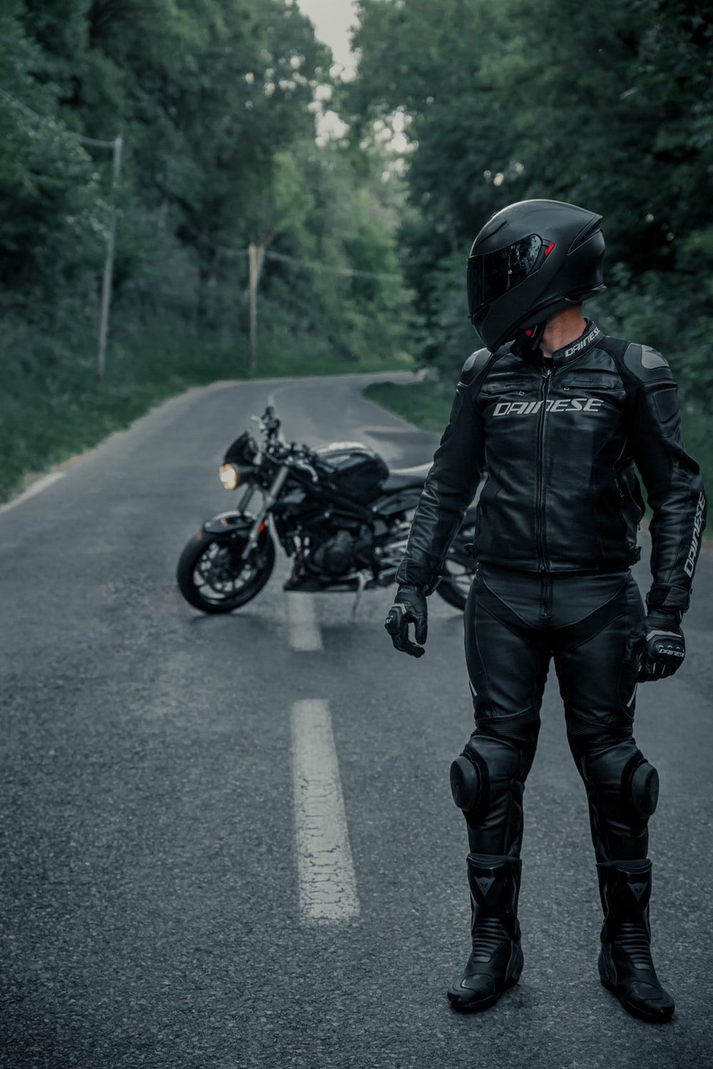 man in black leather jacket and black helmet riding motorcycle on road during daytime photo