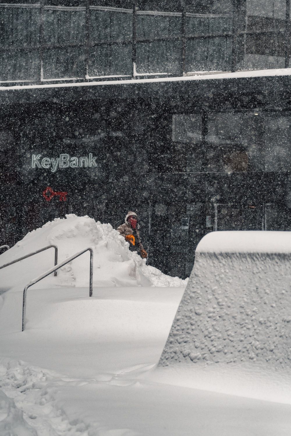 man in red jacket sitting on white snow covered bench during daytime photo