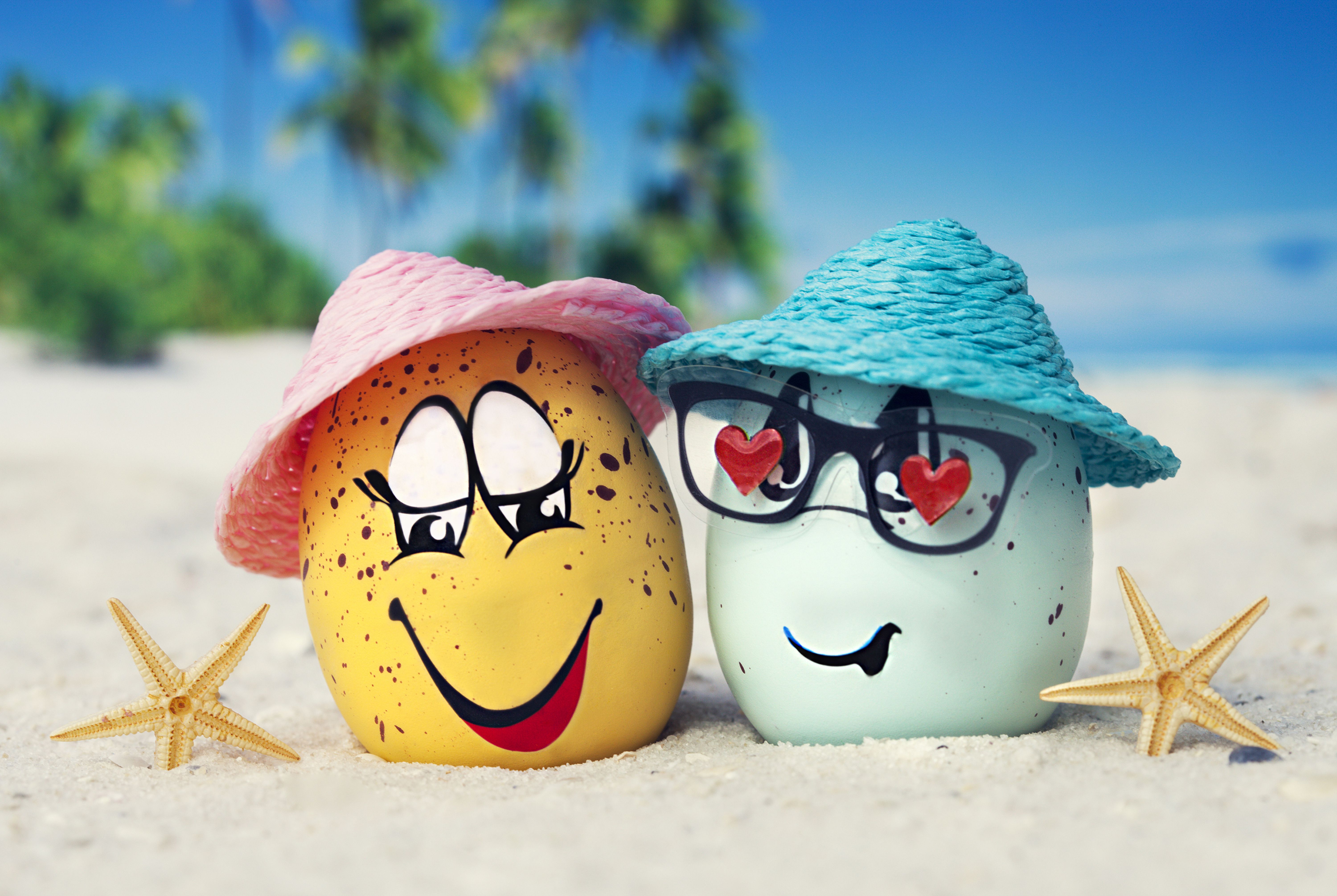 Two eggs in hats on the sand with starfish in summer wallpaper and image, picture, photo
