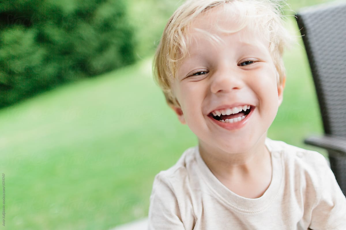 Cute Little Boy Laughing In Yard by Amir Kaljikovic, Joyful