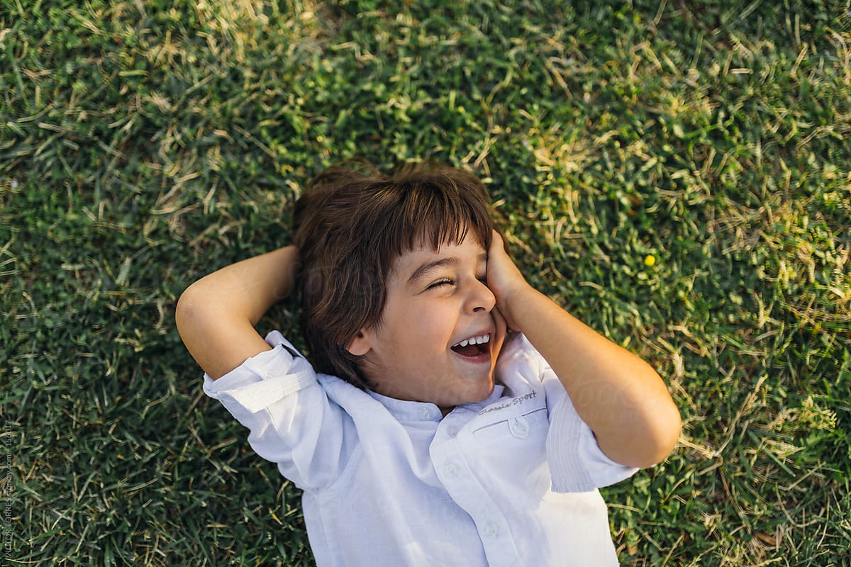 Cute Laughing Kid Lying On Grass by VICTOR TORRES, Summer