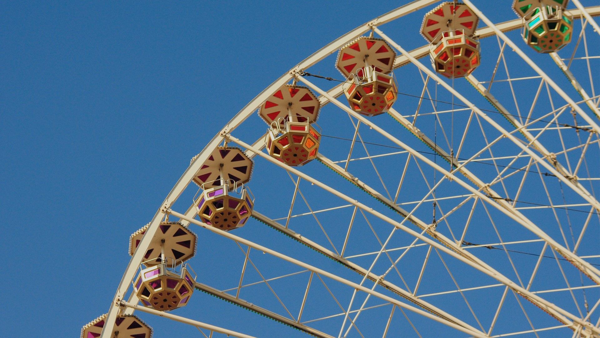 Vintage colorful ferris wheel against a sunny blue sky, retro fun at a summer fair or a carnival. Windows 10 Spotlight Image