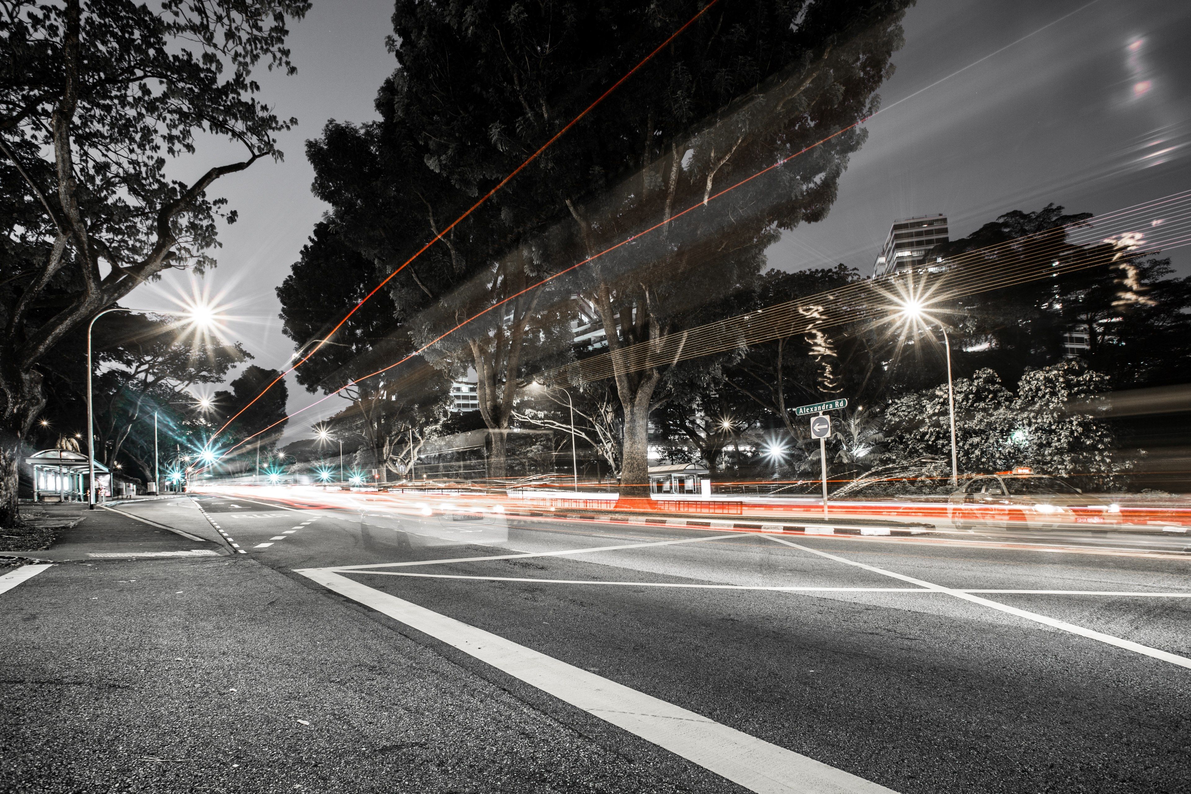 Wallpaper / a desaturated long exposure shot of an empty road with light trails, light trails on an empty road 4k wallpaper