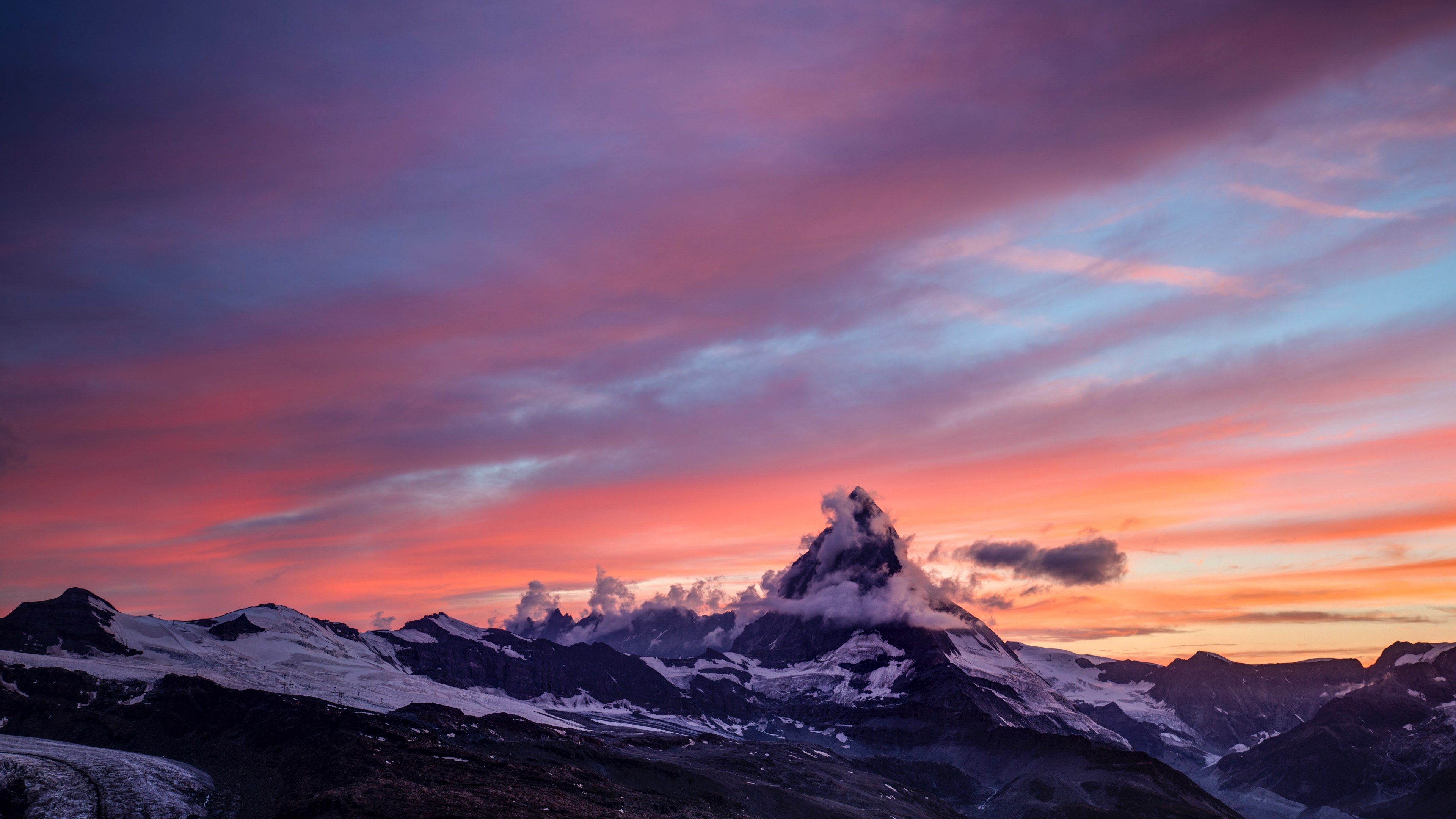 Wallpaper / the sun setting over the snow capped matterhorn mountain with a blue and orange skyline, sunset over matterhorn 4k wallpaper