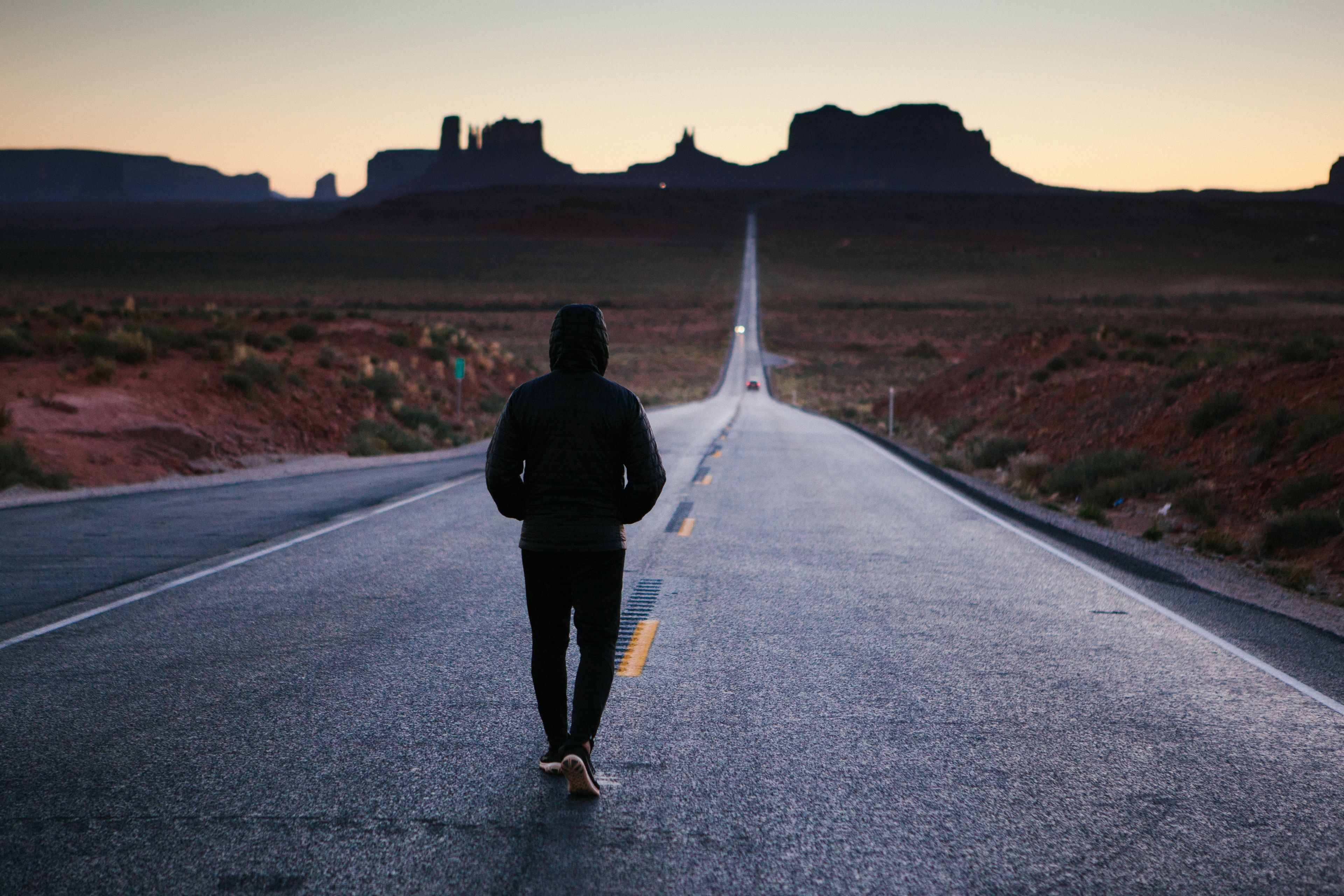 Wallpaper / anonymous person walking alone down a desert country road, sunset at monument valley 4k wallpaper