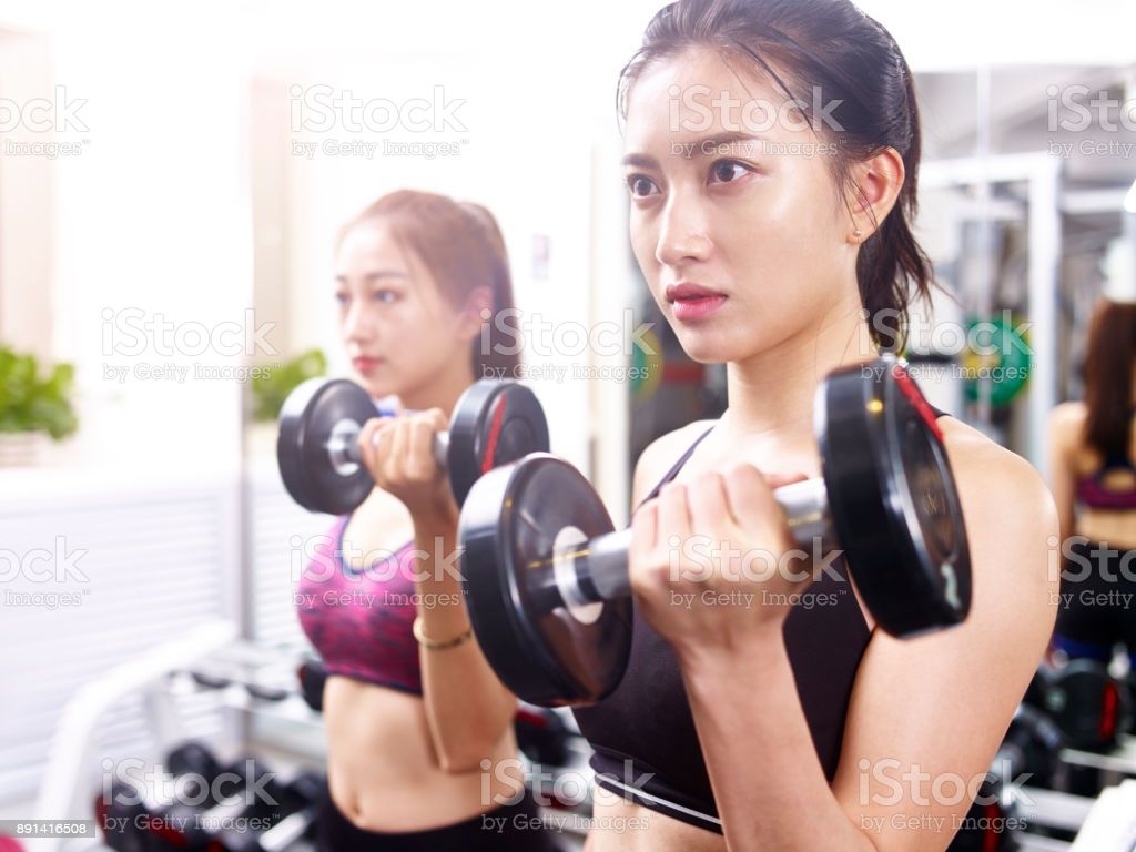 Young Asian Women Working Out In Gym Using Dumbbells Image Now