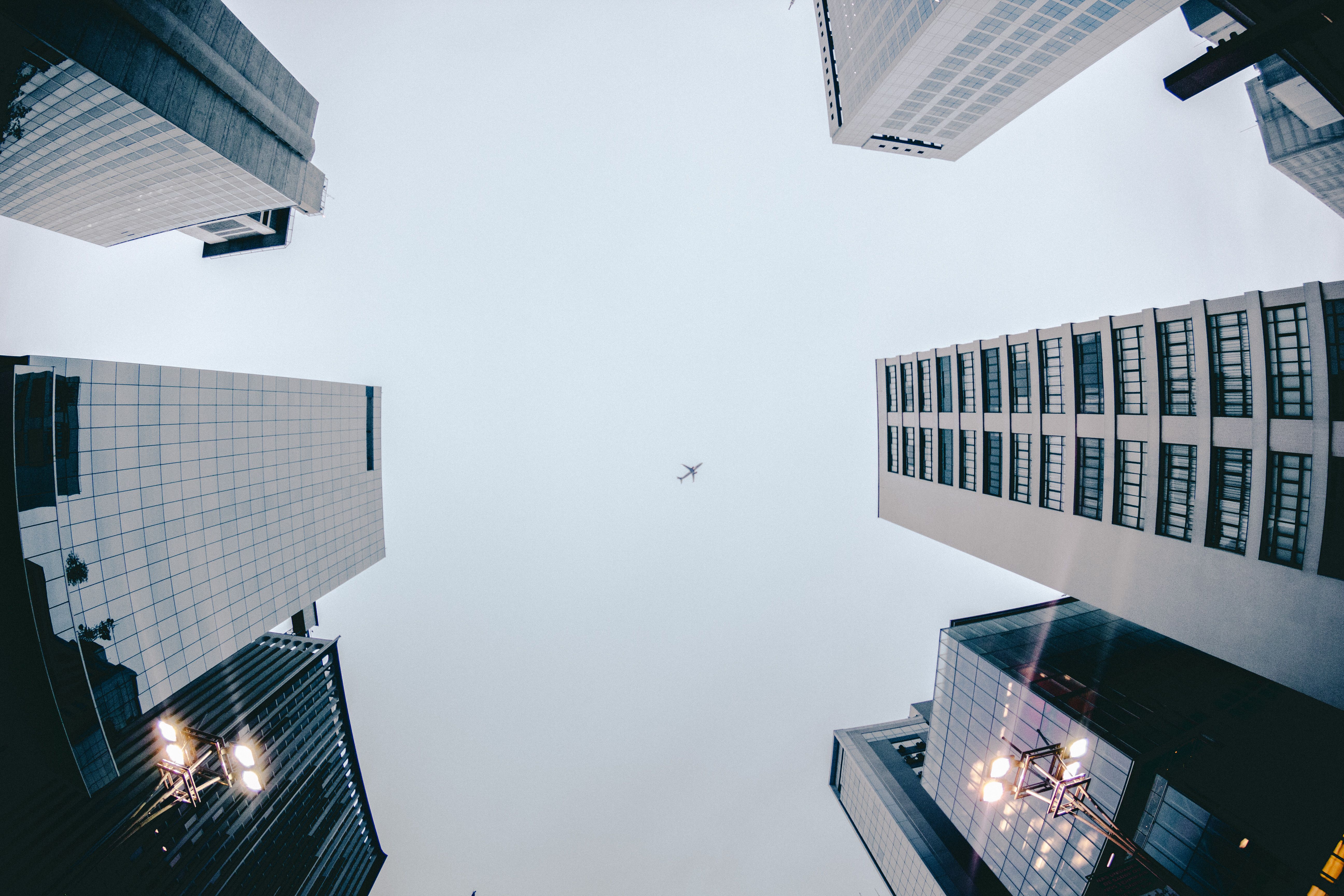 Low Angle Photography of Airplane Flying Above High Rise Buildings wallpaper