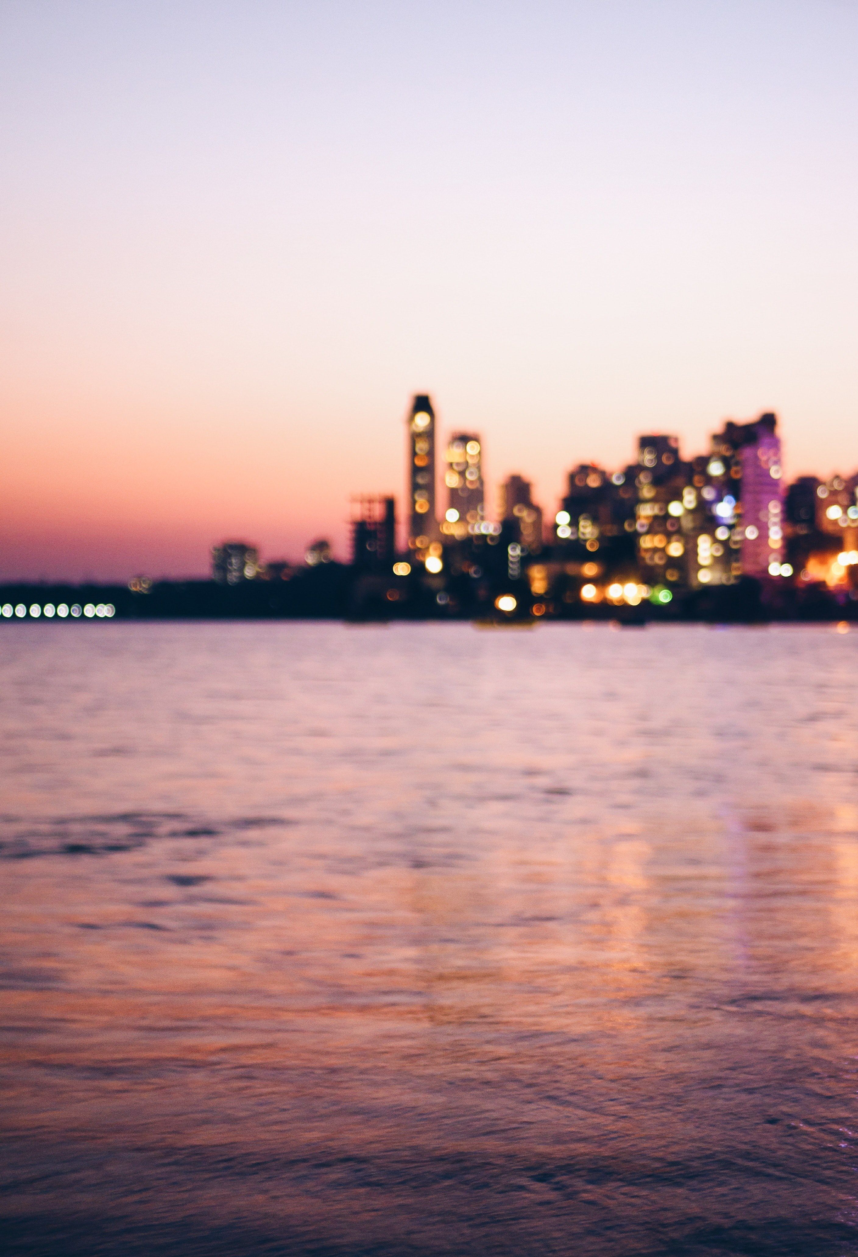 Wallpaper / a blurry city skyline seen from a body of water on an evening, mumbai 4k wallpaper