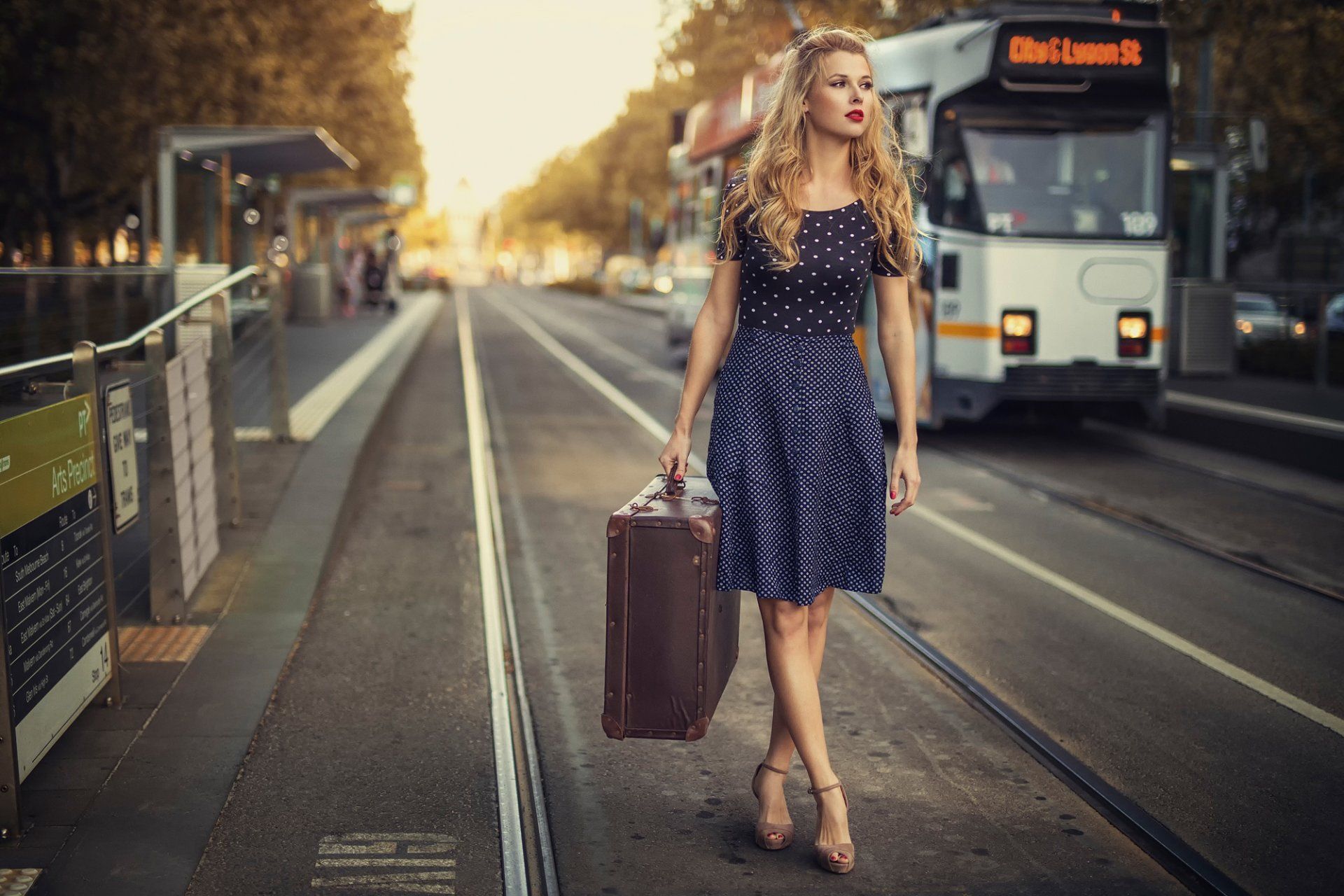 #long hair, #street, #tram, #suitcase, #polka dots, #women, #legs crossed, #blue dress, #women outdoors, #high heels, #red lipstick, #luggage, #model, #blonde, wallpaper. Mocah HD Wallpaper