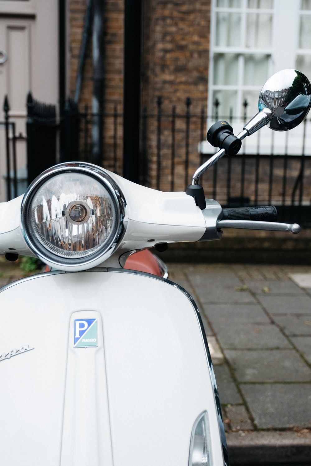 white and blue motor scooter parked beside brown brick wall photo