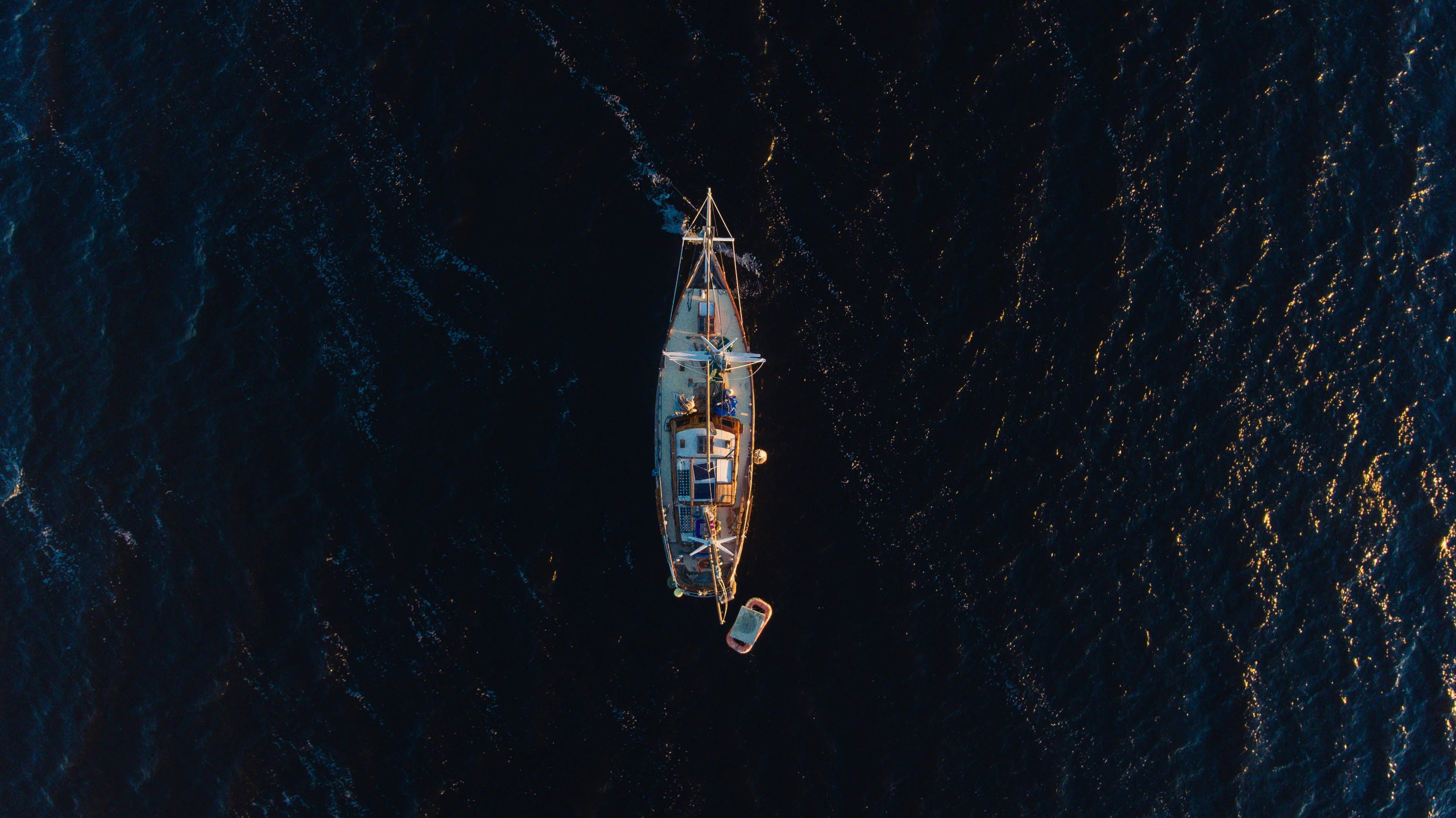 Wallpaper / a drone shot of a boat in the ocean, lost at sea 4k wallpaper