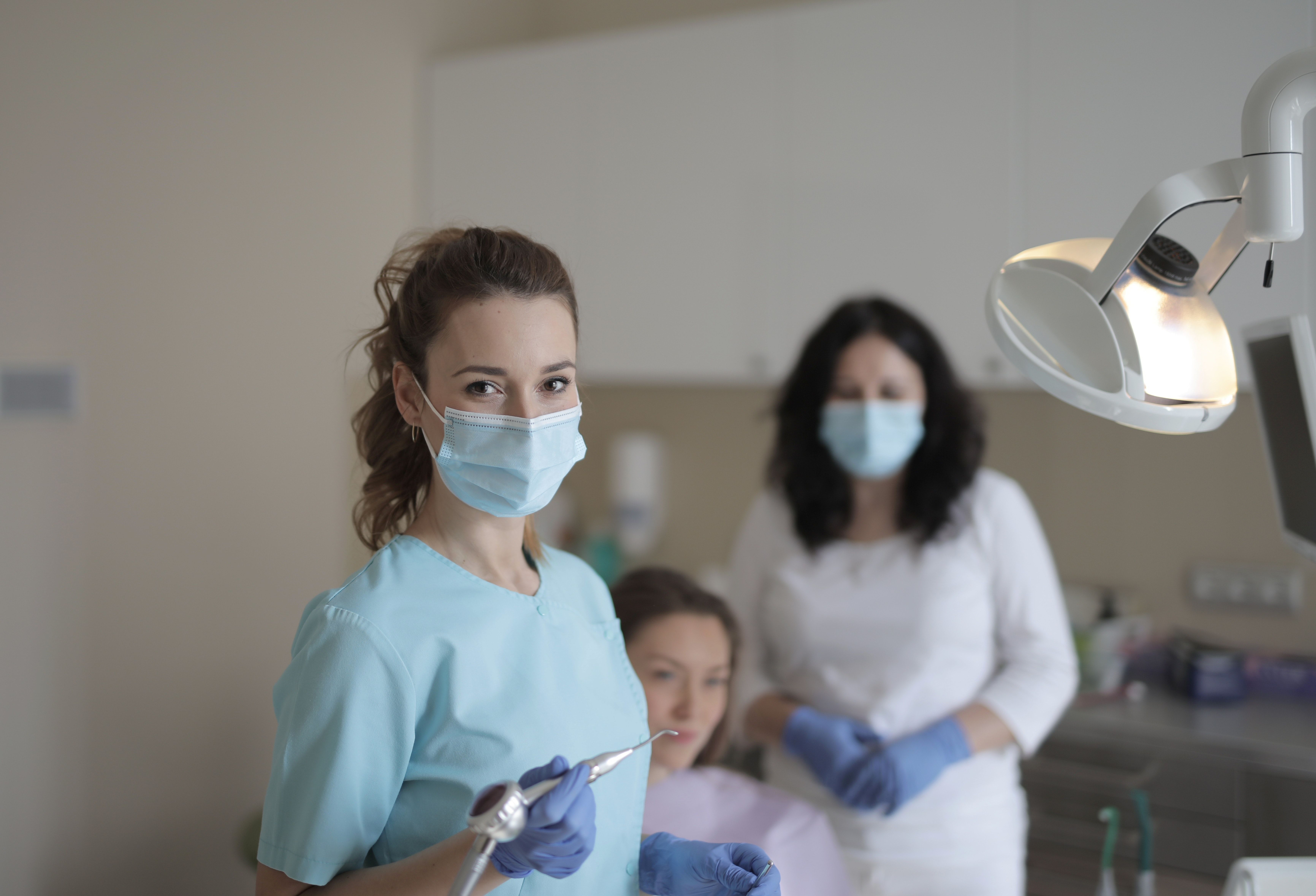 Female dentists treating teeth of patient in modern clinic · Free