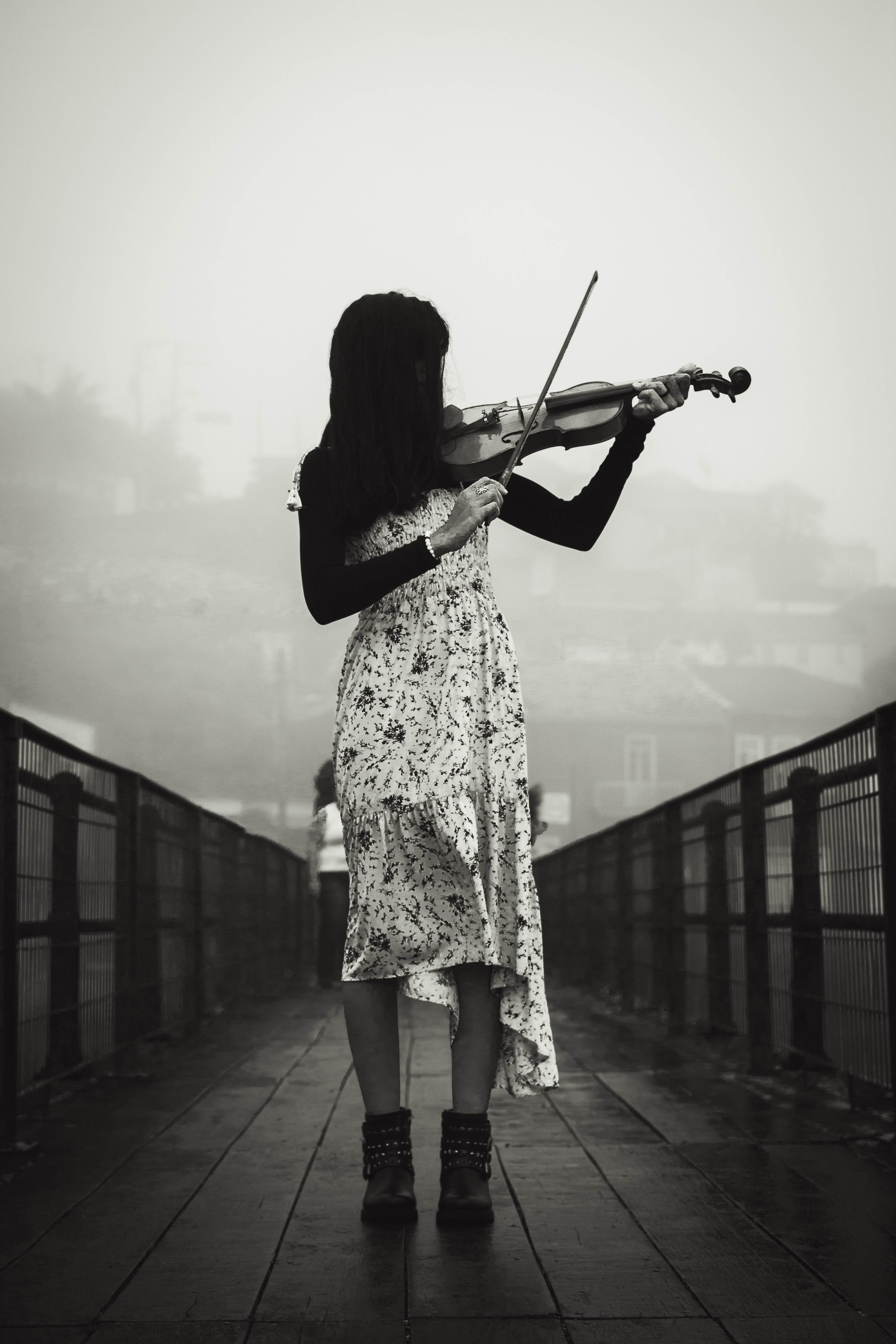 Woman playing violin on bridge in misty day · Free