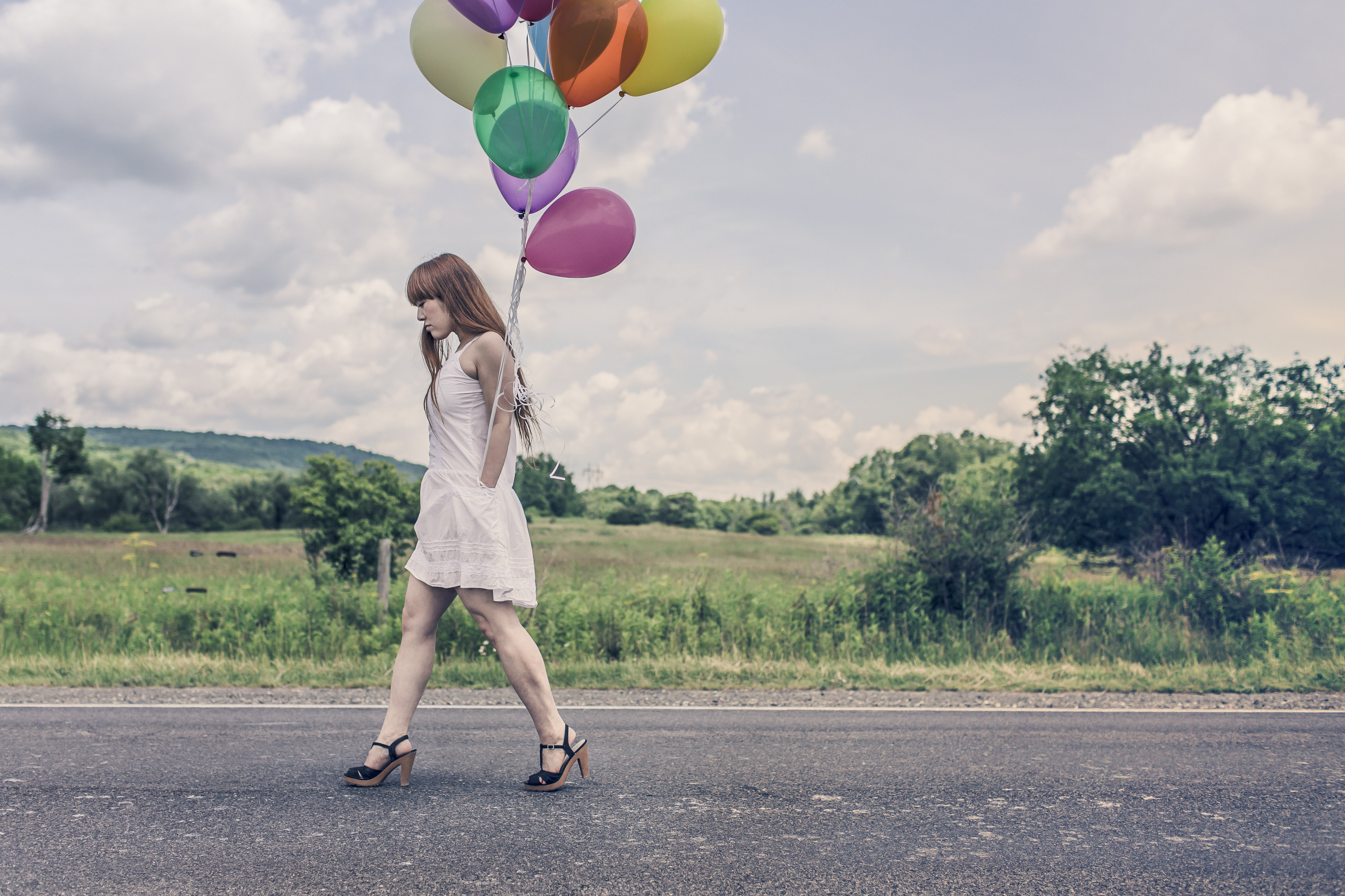 Photography of Woman Walking Near Road Holding Balloons · Free