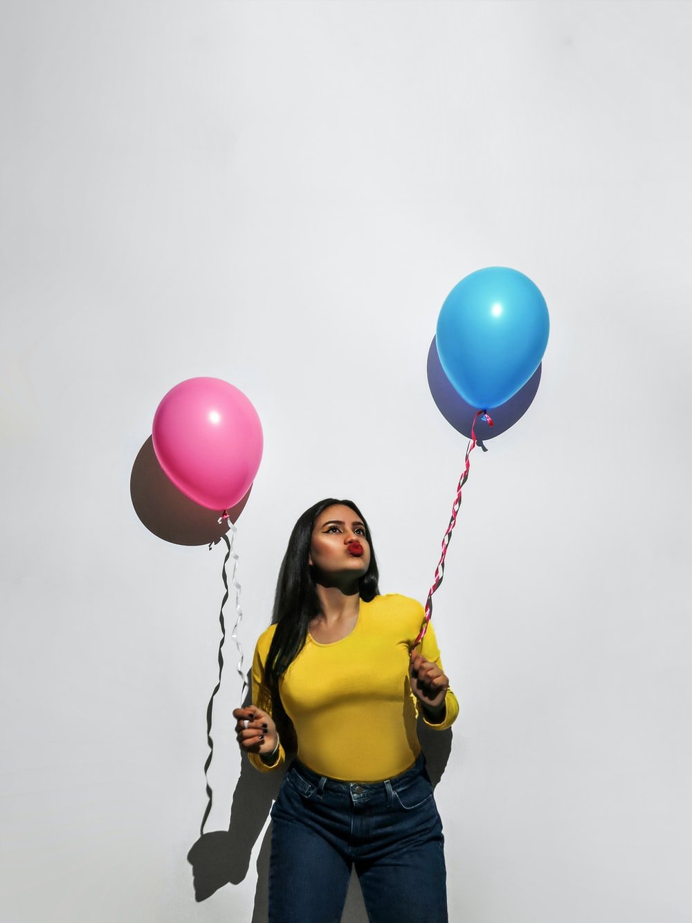 woman in yellow tank top holding balloons photo