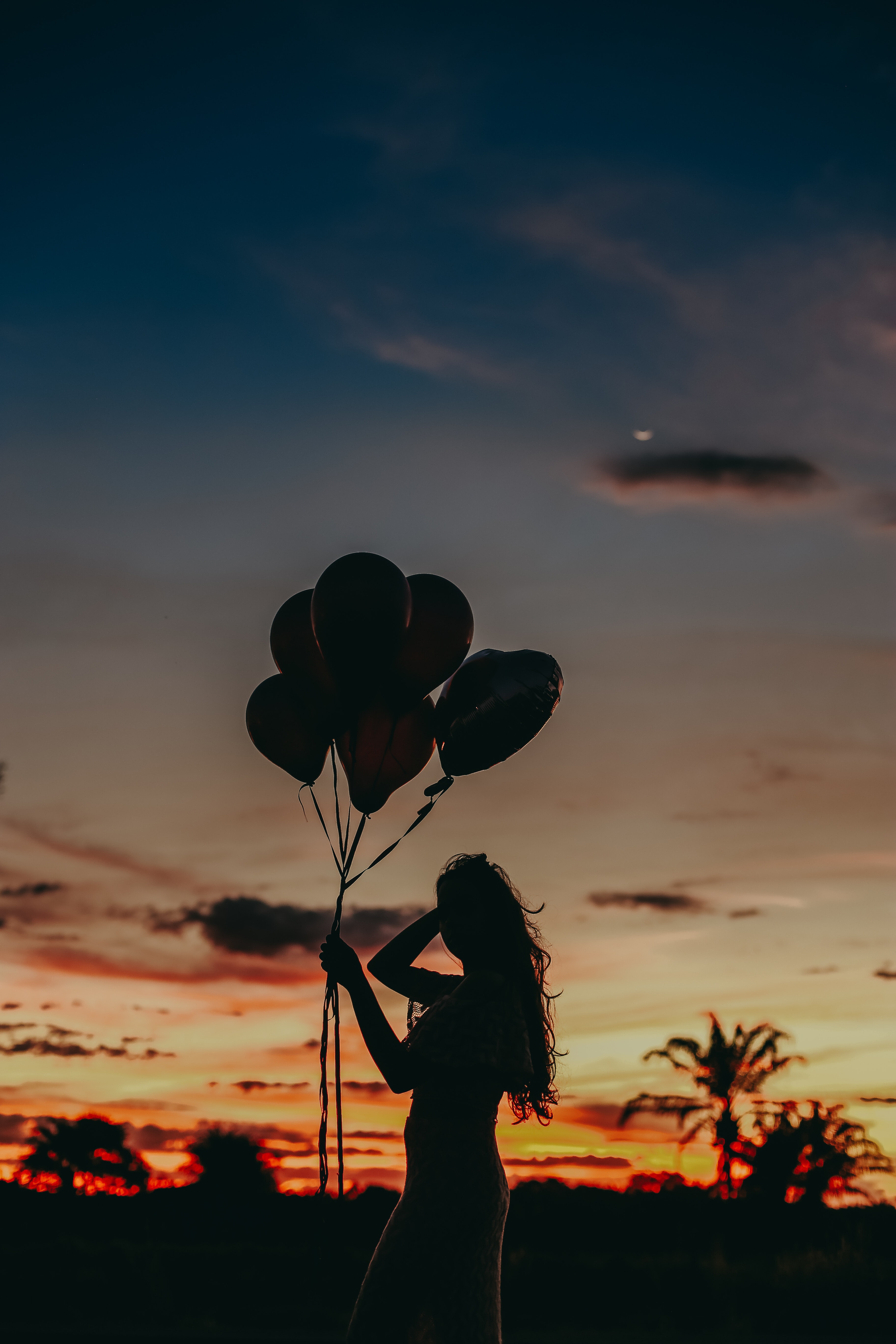 Silhouette of Woman Holding Balloons during Sunset · Free