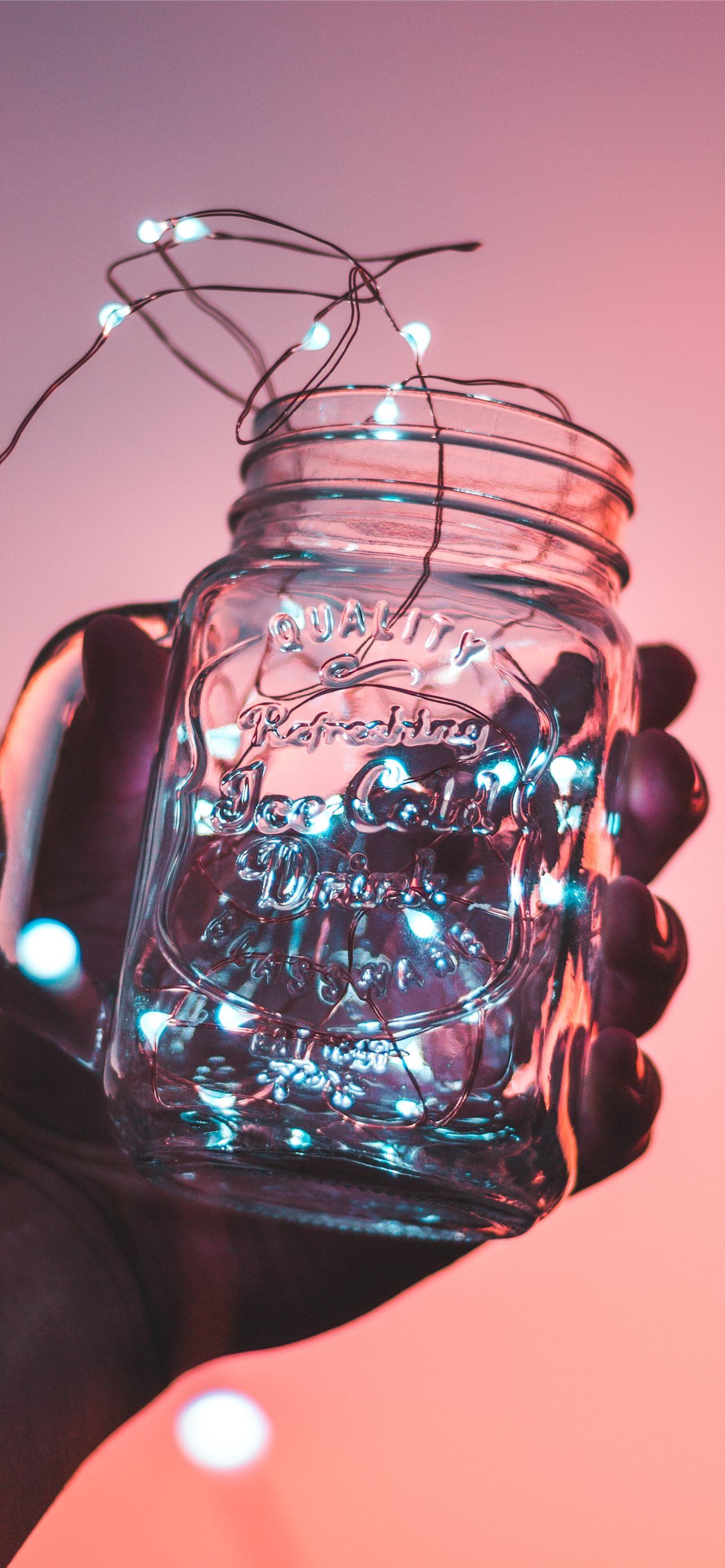 person holding clear glass mason jar with strip li. iPhone 12 Wallpaper Free Download