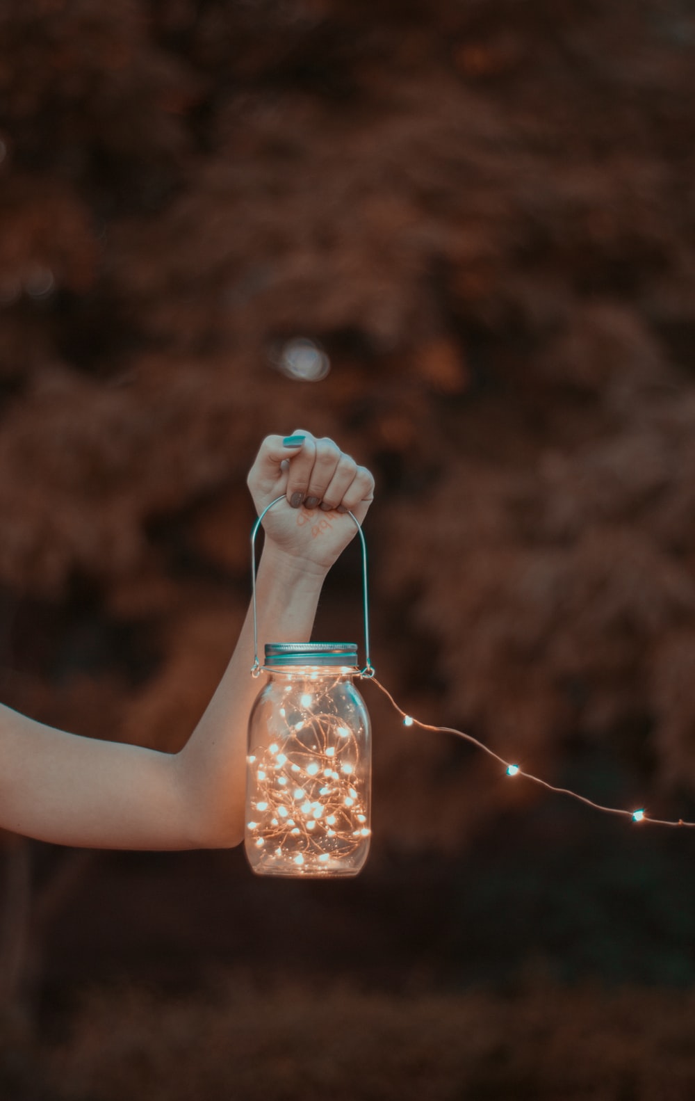 person holding mason jar with string lights photo