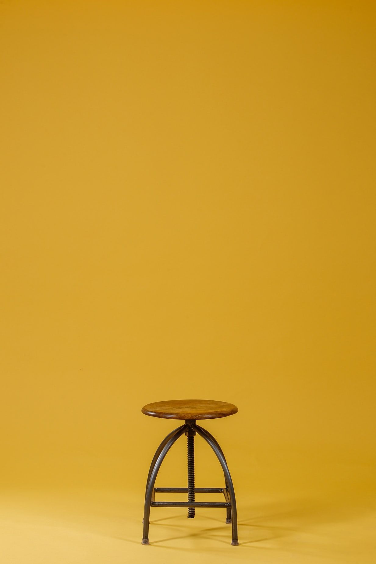 round brown wooden top and black base chair on yellow background photo