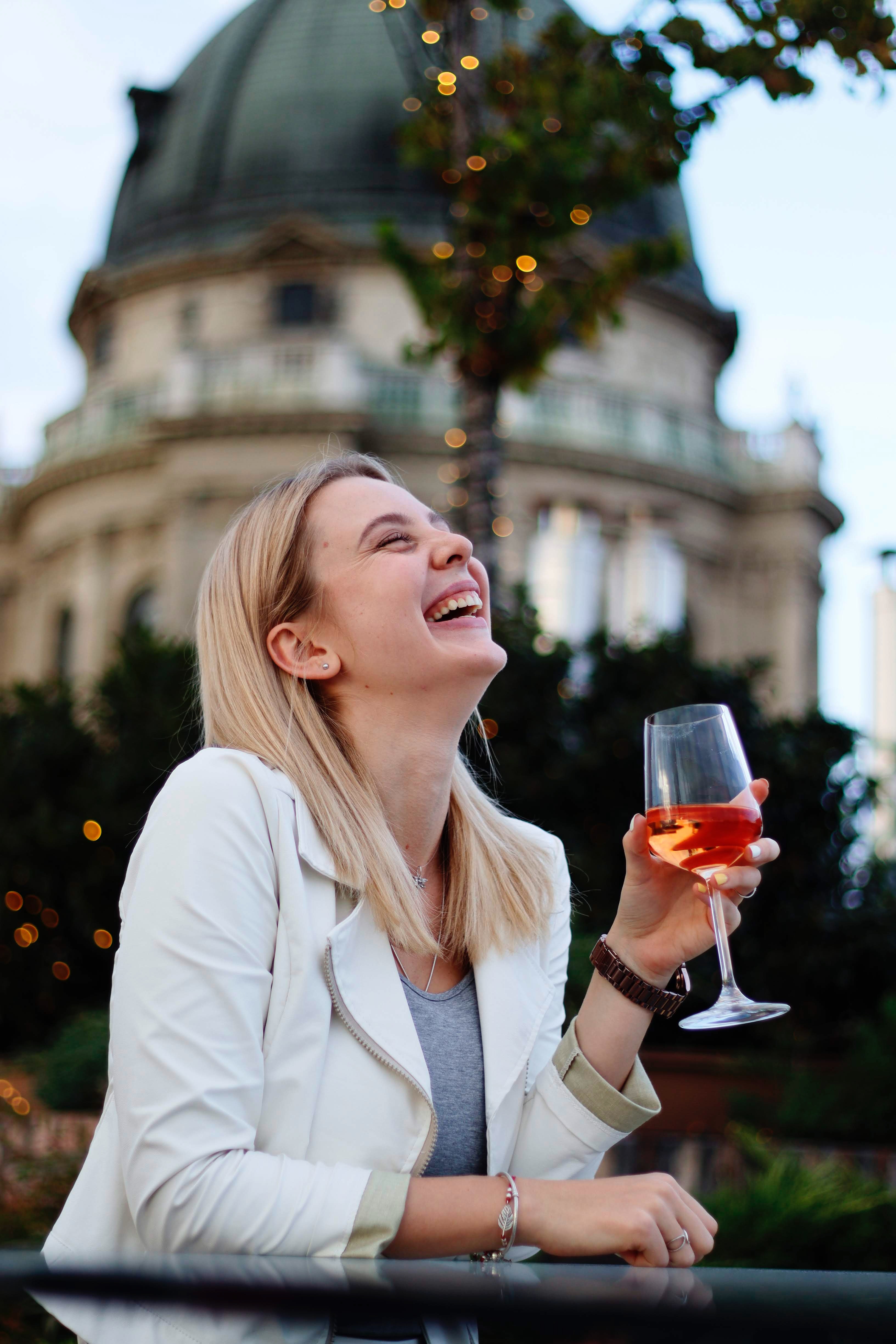 Laughing woman drinking wine in street restaurant · Free