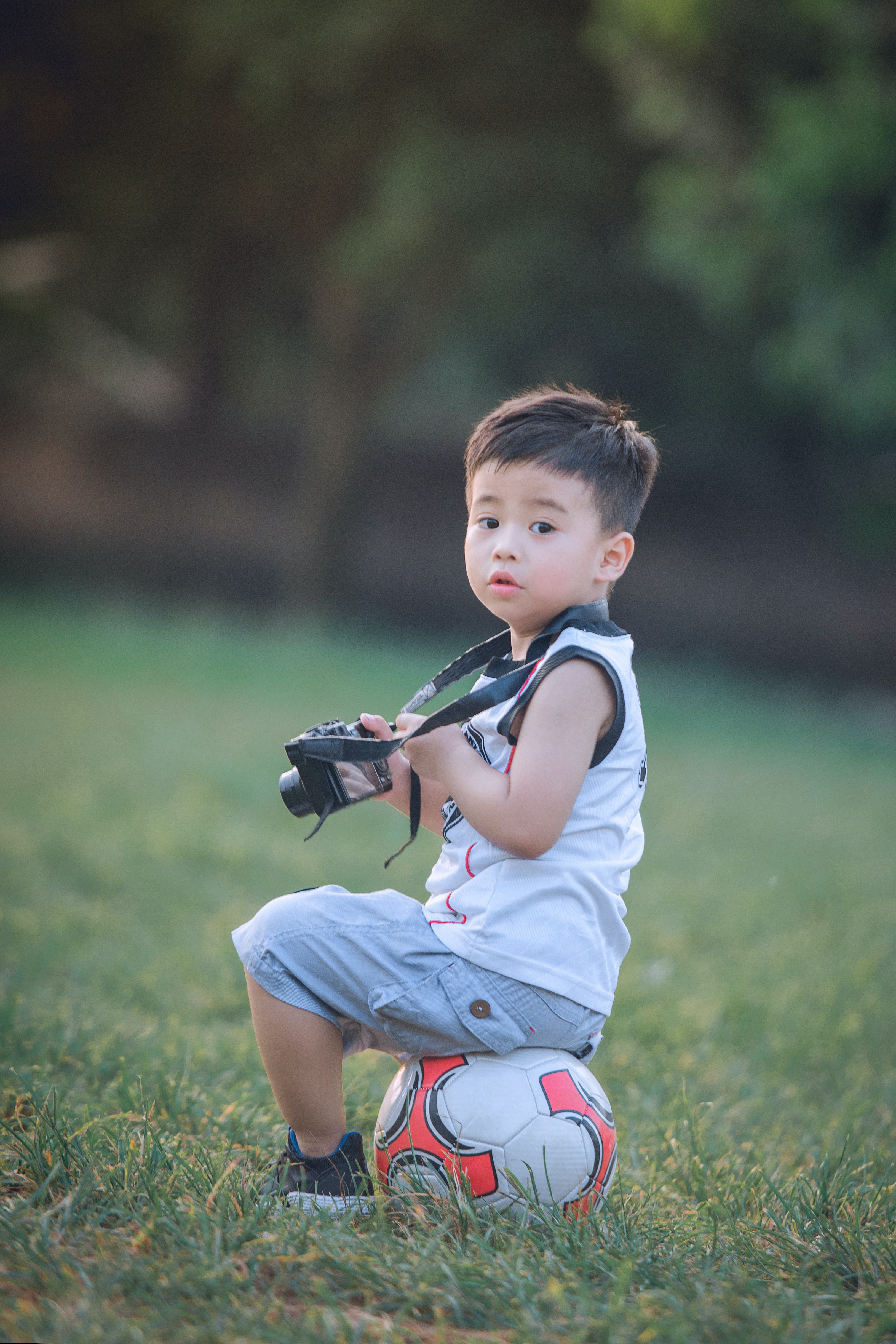 Boy Sitting On Soccer Ball Holding Dslr Camera · Free