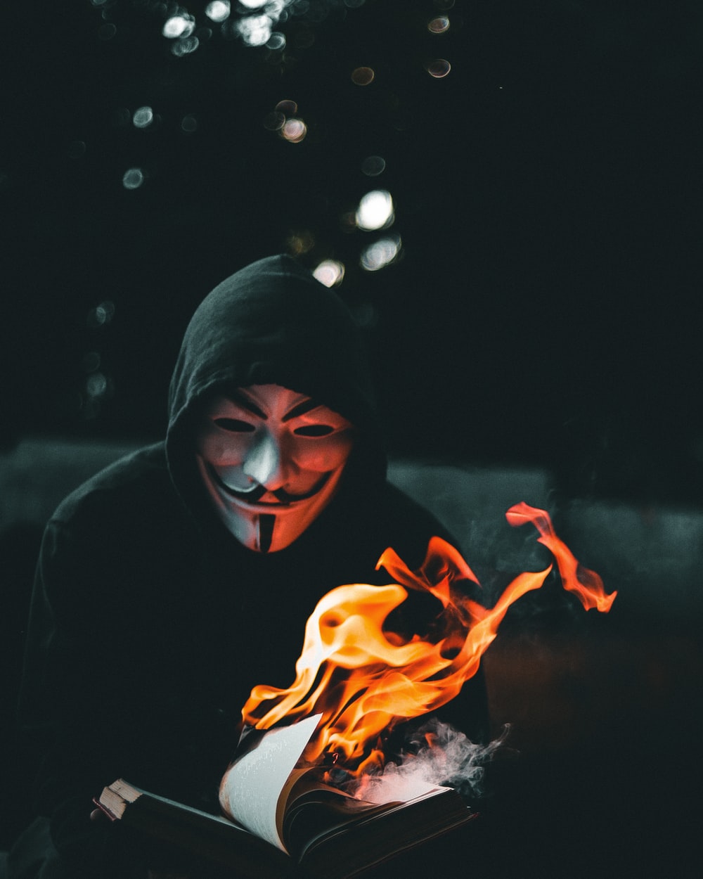 person in black hoodie with orange flame in the background photo