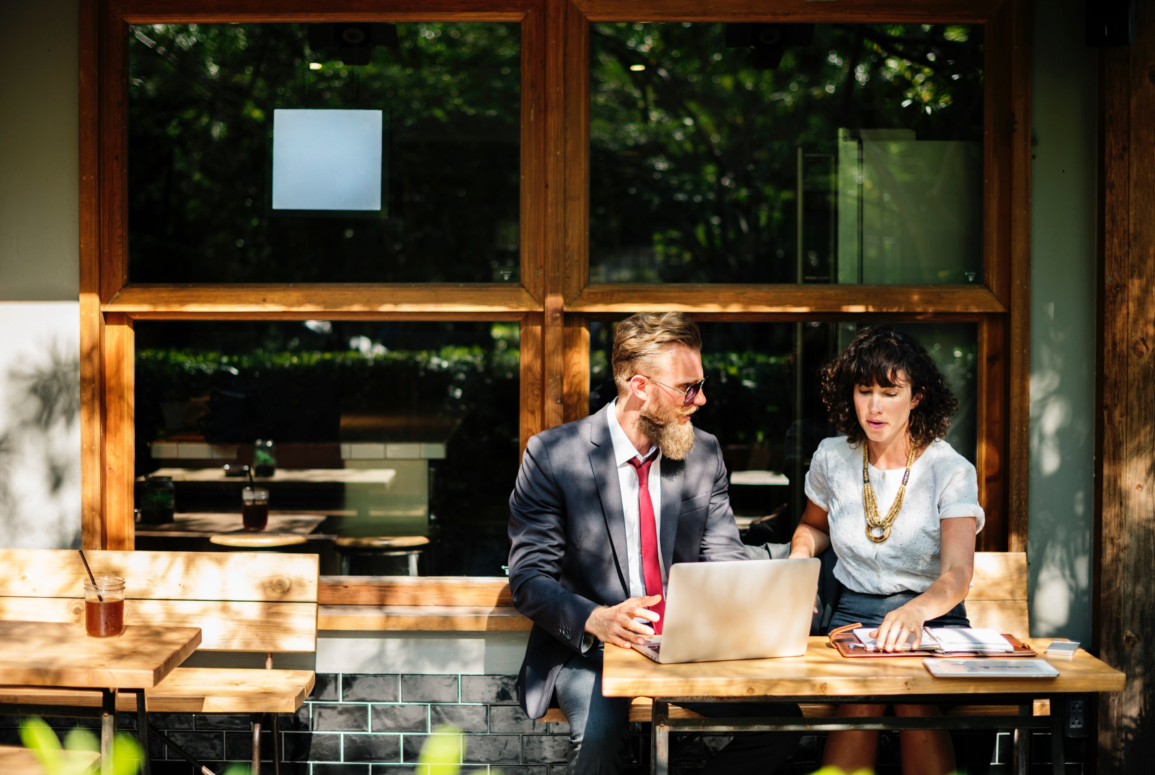 Wallpaper / a man and a woman sitting together at a computer outside of a coffee shop for a business meeting, man and woman business meeting 4k wallpaper