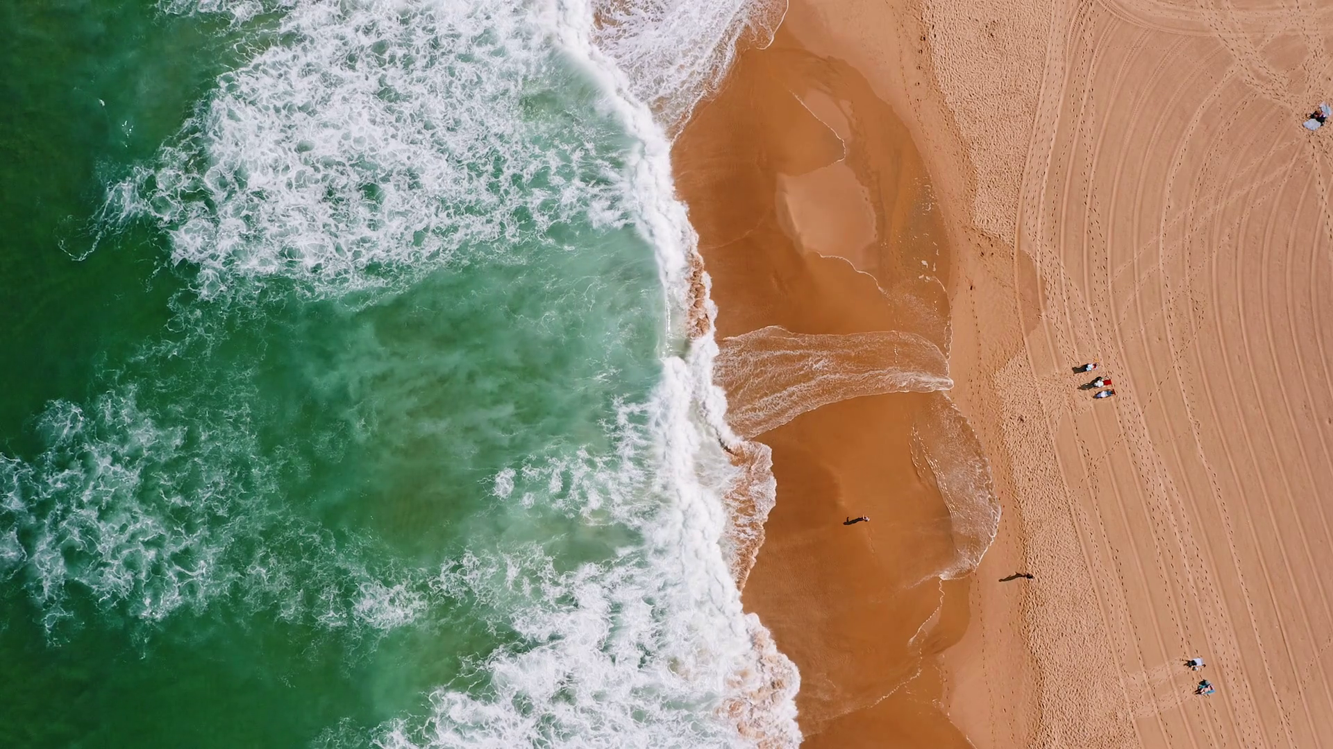 Top aerial view of waves break on tropical yellow sand beach. Bird's eye perspective of emerald green ocean surface and tourist laying in sum and relaxing on holiday Stock Video Footage