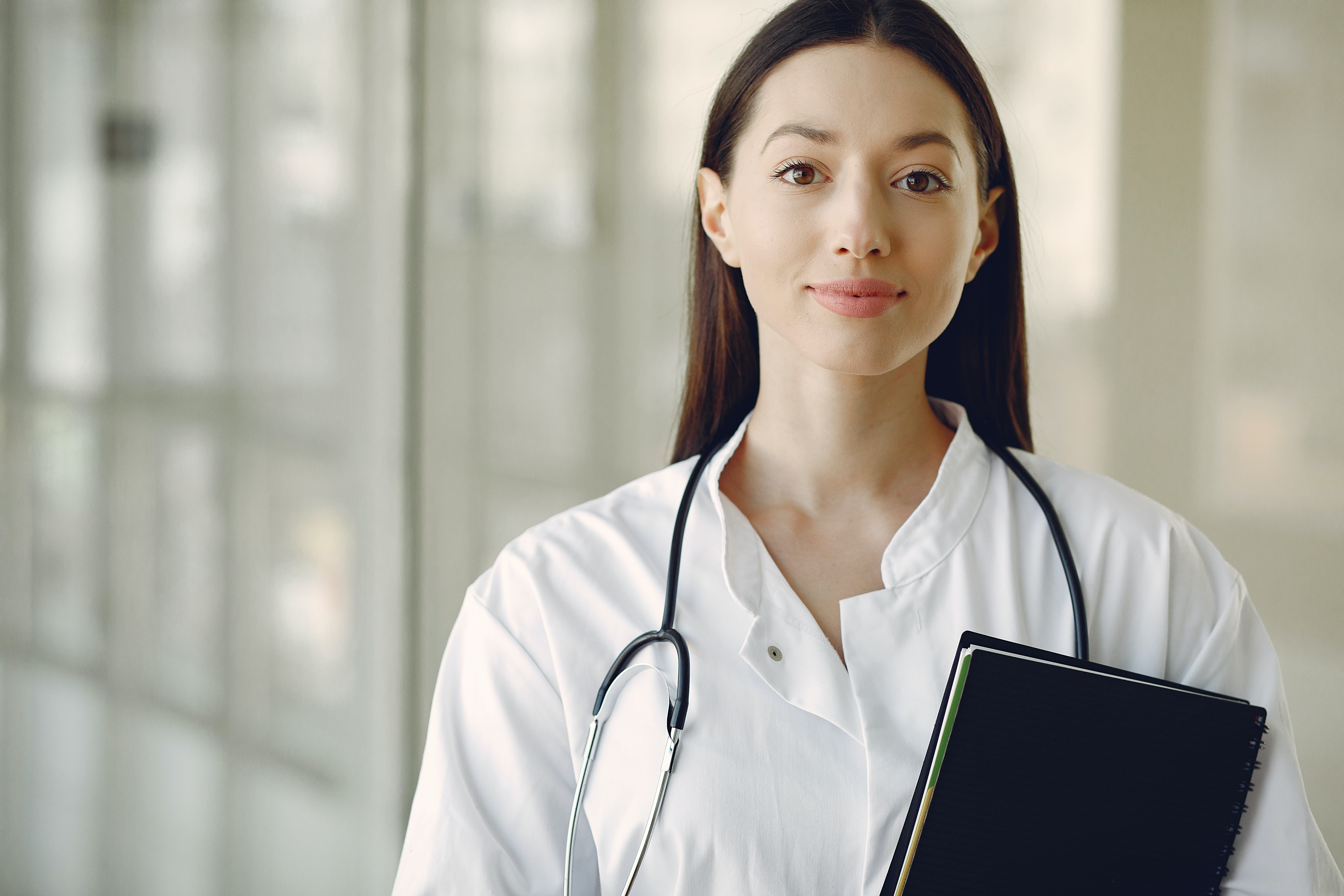 Young doctor in uniform with stethoscope and notebook in medical room · Free